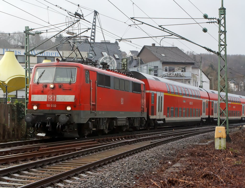 Es wird wieder Sandwich gefahren: Der RE 9 (Rhein-Sieg-Express) Aachen - Kln - Siegen, hat hier am 08.01.2012 den Bahnhof Betzdorf/Sieg verlassen und fhrt weiter in Richtung Siegen. Die Zuglok ist 111 010 und Schublok 111 075-8. Es sind wohl wieder Loks fr diesen Einsatz frei.