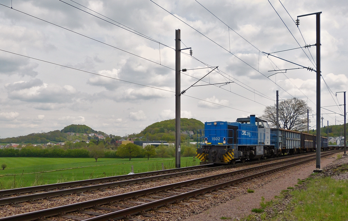 . Die CFL Cargo 1502 (eine MaK G 1206) hat mit ihrem leeren Gterzug am Haken den Bahnhof Belvaux-Soleuvre durchfahren und fhrt nun in Richtung Differdange. Bei den beiden  Hppeln  im Hintergrund handelt es sich um den 422 Meter hohen Zolverknapp (links) und den 403 Meter hohen Bielesser Gaalgebierg. 29.04.2015 (Hans)