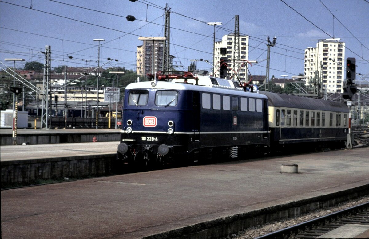 110 228-4 mit blauer Lackierung und rotem DB-Keks mit einem Personenwagen mit Gepäckabteil (BDms 271) in Stuttgart am 04.05.1993.