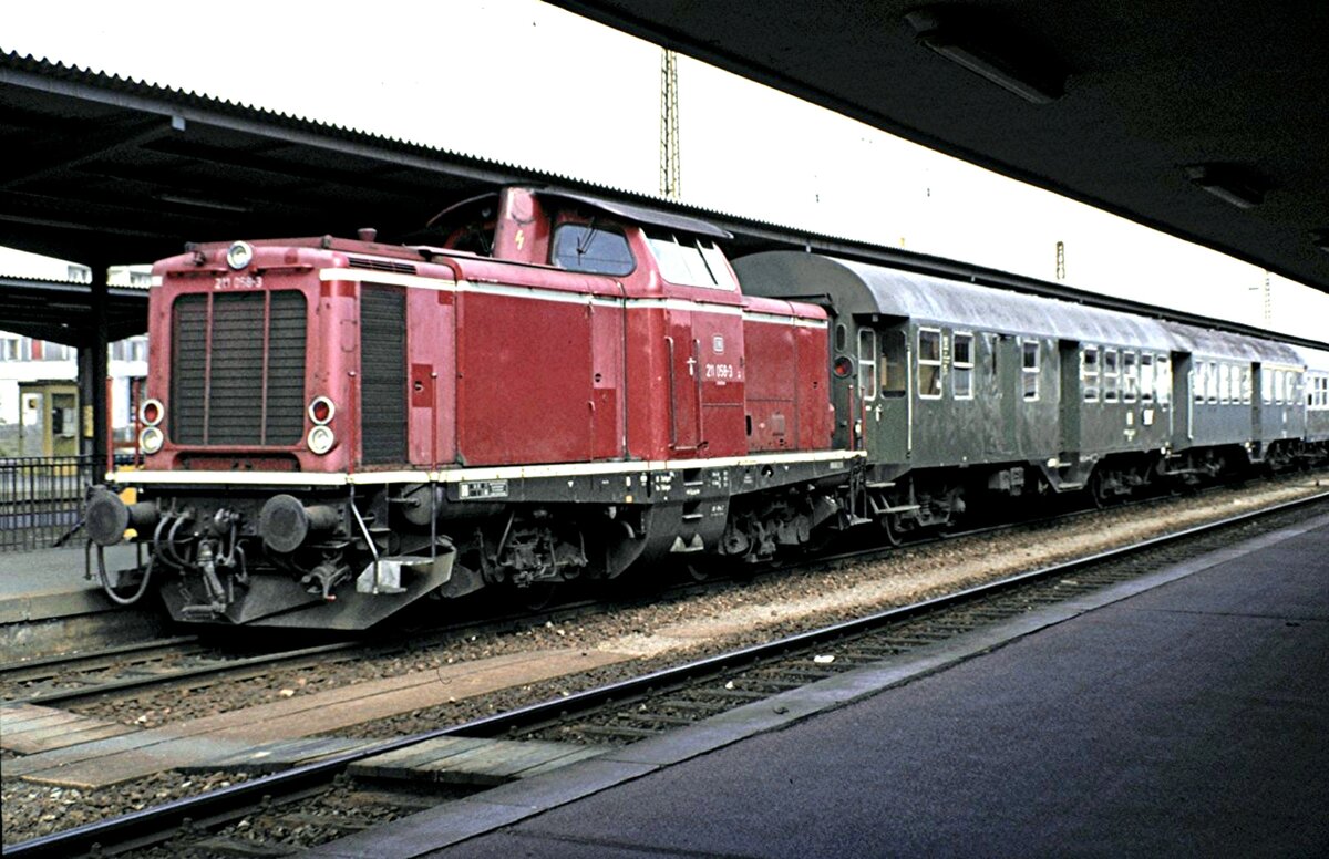 211 058-3 mit zwei Umbauwagen und dahinter Silberlinge in Pforzheim am 17.04.1982.