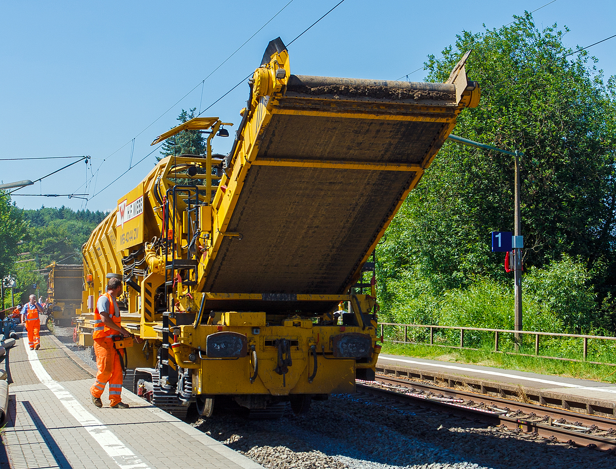 Baustelle im Bahnhof Katzenfurt (Lahn-Dill-Kreis) am 20.07.2013: Der MFS 40/4-A-ZW der H. F. Wiebe, Schweres Nebenfahrzeug 99 80 9052 002-9 D-GBM (ex 97 19 13 502 57-3) bringt den Aushub, auf dem z.Z. gleislosen 2. Gleisbett (fährt auf Raupenfahrwerke), zu einer auf dem noch vorhandenen Gleis stehenden, gleisgebundenen Materialförder- und Siloeinheit MFS 250 (H.F. Wiebe Bezeichnung Bunker-Schüttgut-Wagen BSW 11000).