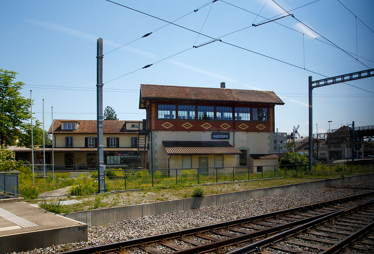 Das Stellwerk beim Bahnhof Kerzers am 18.05.2018, dahinter der Bahnhof. Fotografiert aus einem BLS Regionalzug, daher leider mit Spiegelungen.