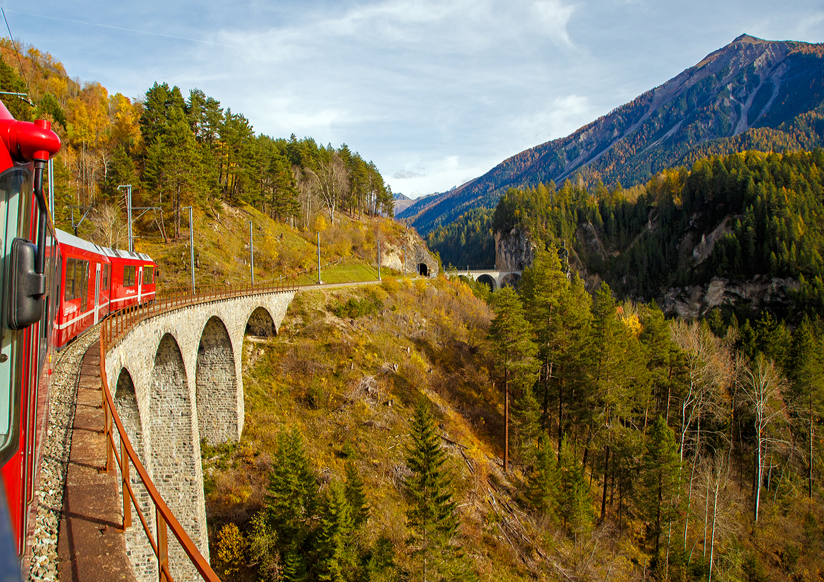 Der RhB ABe 8/12 - 3511  Otto Barblan  (ALLEGRA-Zweispannungstriebzug) mit dem RhB Alvra-Gliederzug als IR von Chur nach St. Moritz, fhrt am 01.11.2019 ber das Schmittentobel-Viadukt (35 m hoch, 137 m lang), danach folgt der 27 m lange Zalaint-Tunnel und das Lehnenviadukt (nicht im Bild), bevor es dann ber das berhmte Landwasserviadukt und gleich anschlieenden durch den 216 m langen Landwasser-Tunnel geht. 