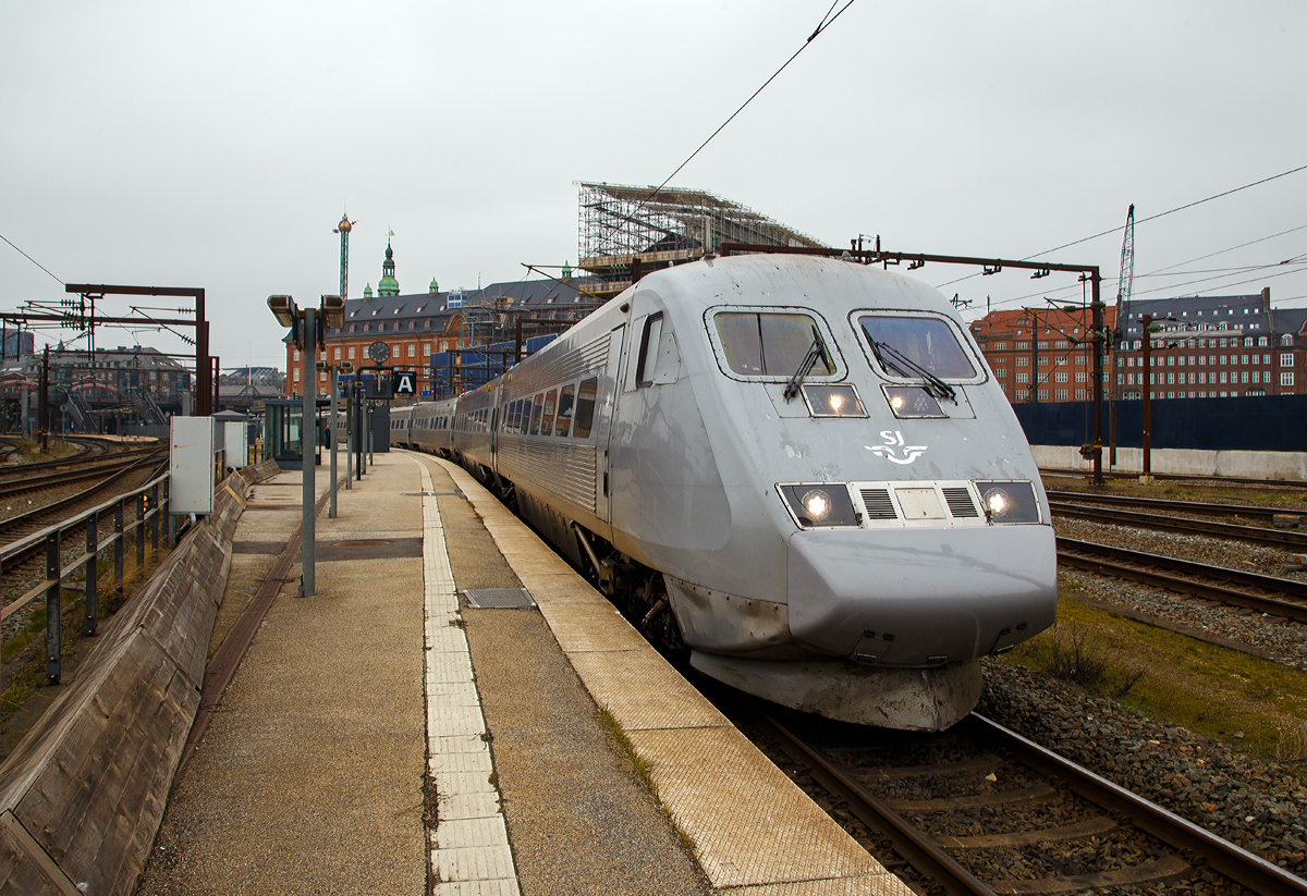 
Der sechsteilige X2K 2033 (S-SJ 93 74 302 2033-8) der SJ (Statens Järnvägar AB, ehemaligen schwedische Staatsbahnen, steht am 20.03.2019 auf Gleis 26 im Hauptbahnhof Kopenhagen (dän. Københavns Hovedbanegård), als X2 542 nach Stockholm Central zur Abfahrt bereit.

Die Baureihe SJ X2 sind Hochgeschwindigkeitszüge der schwedischen Staatsbahngesellschaft SJ AB. Sie sind allgemein unter dem Markennamen X2000 bekannt. Verbindungen mit diesen Zügen werden in Schweden an den Bahnhofs-Anzeigen als Snabbtåg (deutsch Schnellzug) geführt. Ein Zug besteht aus einem Triebkopf, vier bis fünf Mittelwagen und einem Steuerwagen. In einem der Mittelwagen befindet sich ein Zugrestaurant. Die Vielfachsteuerung ermöglicht, zwei Einheiten zu kuppeln. Damit entsteht ein Zug mit elf Wagen und zwei Triebköpfen. 

Durch die im Vergleich zu Mitteleuropa gänzlich andere Bevölkerungsstruktur in Schweden bot es sich nicht an, teure Hochgeschwindigkeitsstrecken zu bauen. Die hügelige und bergige Landschaft Schwedens verteuerte Neubaustrecken noch zusätzlich.

Daher entschieden sich die Schwedischen Staatsbahnen (SJ) für einen Triebzug der Baureihe X2 mit Neigetechnik, mit dem bestehende Strecken schneller befahren werden können. Die Bezeichnung X2000 wurde als Produktname des Hochgeschwindigkeitsverkehrs gewählt. Wobei an den Bahnhofs-Anzeigen sucht man vergeblich an dieser Bezeichnung, sondern sie werden als Snabbtåg (deutsch Schnellzug) angezeigt.

Die Züge sind vollklimatisiert. Die vorgesehene fahrplanmäßige Höchstgeschwindigkeit lag bei 200 km/h, die Züge waren technisch für 210 km/h ausgelegt. Zehn der zwanzig Einheiten waren für die Strecke Stockholm–Göteborg bestimmt, weitere Garnituren sollten auf den Strecken Stockholm–Malmö und Stockholm–Östergötland eingesetzt werden. Die Züge wurden im Werk Västerås der ABB zu einem Stückpreis von 100 Millionen Schwedischen Kronen gebaut; die Entwicklung der Züge hatte bis 1989 zwei Milliarden Kronen gekostet.

Jeder Triebkopf besitzt vier Drehstrom-Asynchronmotoren. Die Steuerung erfolgt mittels GTO-Thyristoren mit einer Frequenz zwischen 0 und 120 Hz. Die maximale Achslast liegt bei 18,5 Tonnen.

Die Neigetechnik wird richtungsabhängig von einem Beschleunigungsmesser im führenden Fahrzeug gesteuert. Der Neigungswinkel ist abhängig von Geschwindigkeit und Bogenradius, er wird in jedem Wagen an den Drehgestellen gemessen und hydraulisch eingestellt. Die Neigung liegt bei maximal 6,5 Grad, die Neigungsänderung bei höchstens vier Grad pro Sekunde. Bei Geschwindigkeiten unter 70km/h ist die Neigetechnik nicht aktiv. Die Technik wird so eingeschränkt, dass ein Reisender auf einem Eckplatz des Wagens nie 30 cm höher oder tiefer als ein anderer im selben Wagen sitzt. Die Triebköpfe selbst verfügen über keine Neigetechnik. Ein besonderer Lokführersitz mit verstärktem Seitenhalt gleicht die erhöhte Seitenbeschleunigung aus.

Eine Besonderheit der Züge ist die radiale Einstellbarkeit der einzelnen Achsen in jedem Drehgestell. Auf den bogenreichen Strecken Schwedens kann sich so jede Achse einzeln der Strecke anpassen. Dadurch reduziert sich die Reibung erheblich, was zu Einsparungen beim Energieverbrauch und geringerem Materialverschleiß führt.

In den Jahren 2000 bis 2001 wurden die Züge X2 2031–2034 und 2036–2043 für den Betrieb in Dänemark umgerüstet, damit der Einsatz auf der Öresundverbindung möglich wurde. Neben dem Einbau der dänischen Zugbeeinflussungseinrichtung beinhaltete dies die Umrüstung der Triebköpfe für den Zweifrequenzbetrieb, da die dänischen Fernstrecken abweichend mit 25kV bei 50Hz elektrifiziert sind. Die Baureihenbezeichnung dieser Triebköpfe änderte sich auf X2K.

Der Zug hat spürbare Auswirkungen auf die SJ und den schwedischen Schienenverkehr hinterlassen. Steigende Passagierzahlen, verbunden mit sinkenden Betriebsausgaben bei gleichzeitig beschleunigten und effizienteren Einsätzen halfen den SJ, profitabel zu werden.

TECHNISCHE DATEN:
Hersteller: ABB (Västerås), Kalmar Verkstad (Kalmar)
Baujahre: 1989 bis 1998
Gebaute Garnituren: 43
Spurweite: 	1435 mm (Normalspur)
Achsformel: Bo'Bo' (Triebkopf)
Länge über Kupplung: 140m (fünfteilig) / 165m (sechsteilig)
Leergewicht: 344 t (fünfteilig) / 391 t (sechsteilig)
Höchstgeschwindigkeit: 200 km/h
Dauerleistung: 3.260kW
Stromsystem: 15 kV 16,7 Hz AC (Baureihe X2K zusätzlich 25kV/50Hz AC für den Verkehr nach Dänemark)
Sitzplätze: 	263 (fünfteilig) / 311 (sechsteilig)
