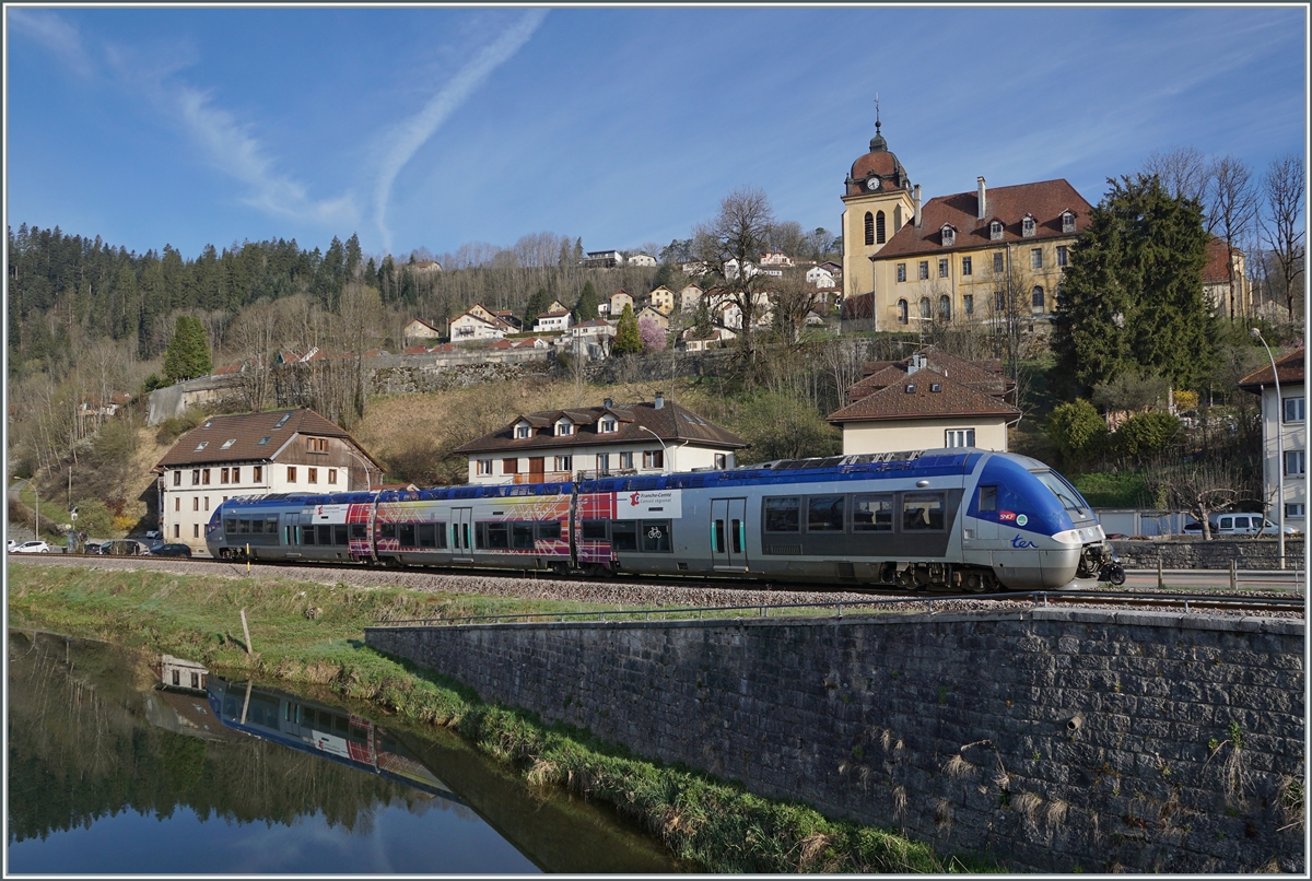 Der SNCF X 76679/680 verlässt als TER 18108 von La Chaux de Fonds nach Besançon den Ort Morteau. Im Hintergund ist die Kirche Notre-Dame de l'Assomption zu sehen.  

16. April 2022