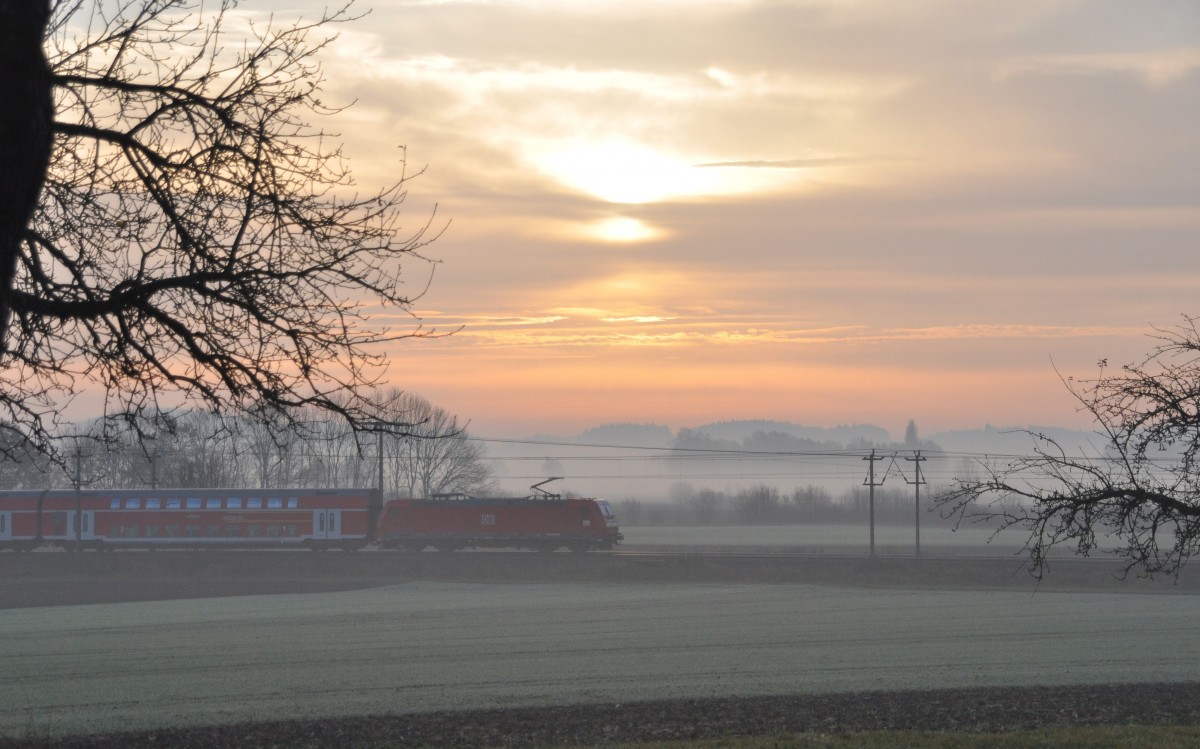 Die 146 223-3 kommt mit einem Doppelstockzug aus Augsburg durch den Frühdunst bei Sonnenaufgang in Neu-Ulm Pfuhl durch, am 21.11.2009.