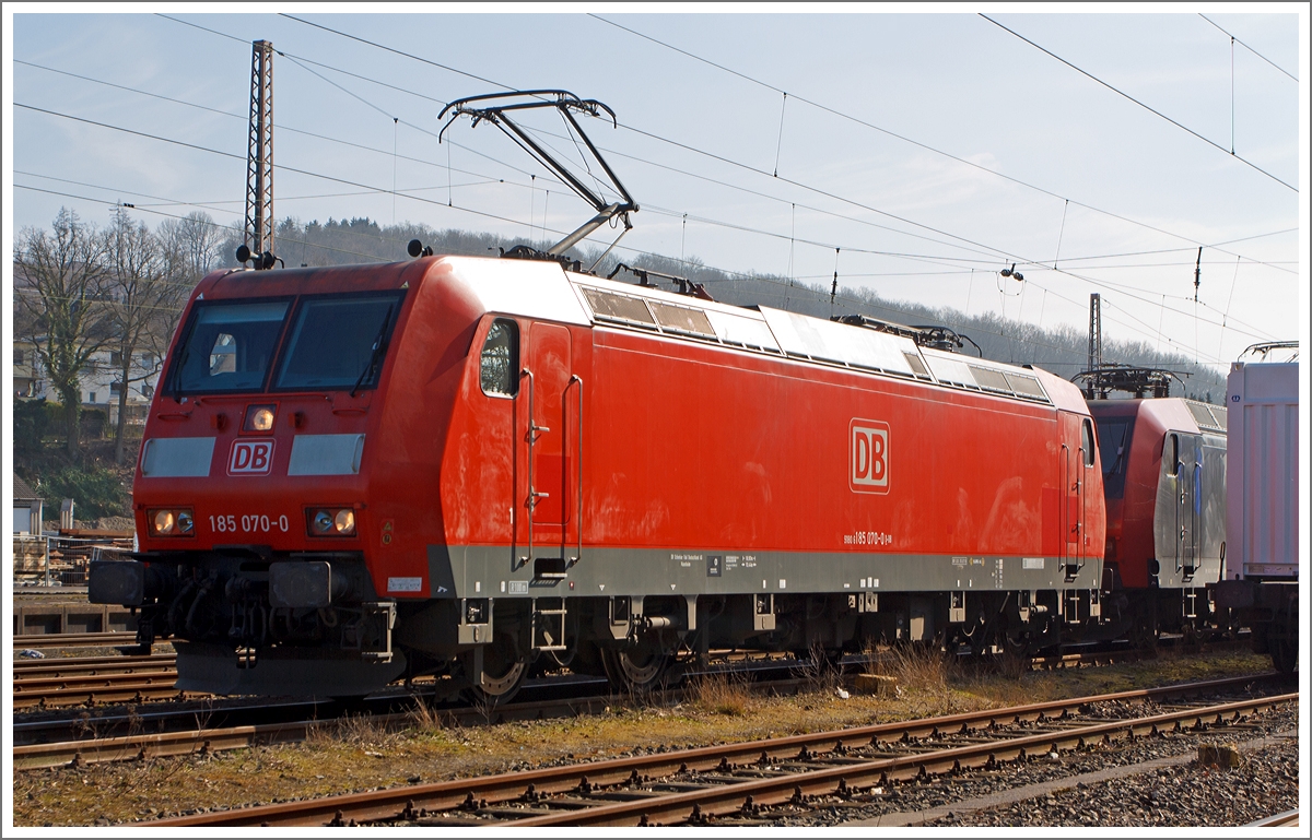 Die 185 070-0 der DB Schenker Rail Deutschland AG steht am 08.03.2014 in Kreuztal im Abstellbereich und macht sich mit der (verdeckten) 145 084-0 zur Fahrt zum Rangierbahnhof bereit, um einen Güterzug zuübernehmen. 

Die TRAXX F140 AC1  (BR 185) wurde 2002 bei Bombardier in Kassel unter der Fabriknummer 33485  gebaut. Sie trägt die NVR-Nummer 91 80 6185 070-0 D-DB und die EBA-Nummer EBA 99A22A 070.