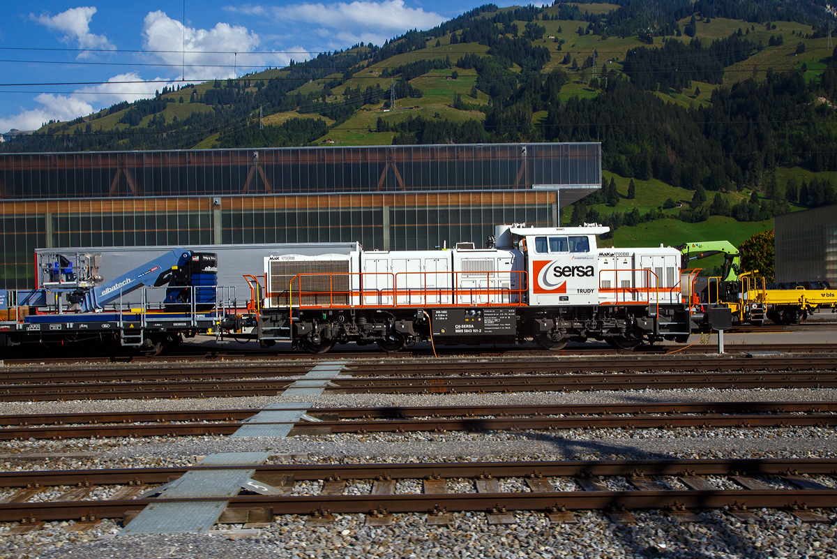 Die Am 843 151 „Trudy“ (98 85 5843 151-2 CH-SERSA) der Sersa (Rhomberg Sersa Rail Group), eine Schweizer Version der MaK G 1700-2 BB, ist am 08.09.2021 in Frutigen abgestellt (aufgenommen aus einem Zug).

Die Am 843 wurde 2004 von Vossloh in Kiel (ehem. MaK) unter der Fabriknummer 5001492 gebaut und an die Sersa AG (CH) geliefert. Die angeschriebene Bezeichnung „MaK G 1700 BB“ ist eigentlich nicht ganz richtig, denn die Schweizer Version Am 843 unterscheidet sich etwas von der MaK G 1700 BB.

Die Schweizerischen Bundesbahnen (SBB) bestellten bei Vossloh zunächst 59 Lokomotiven der Baureihe Am 843. Diese Lokomotiven werden im schweren Rangier- und leichten Streckendienst eingesetzt. Dazu gehört neben dem Rangierdienst in den größeren Rangierbahnhöfen und auf Stationen auch der Zustelldienst mit Streckenfahrten im Nahbereich. Ein weiteres Einsatzgebiet für die Lokomotiven besteht im Bau- und Interventionsdienst.

Um die Am 843 für diese sehr unterschiedlichen Aufgaben möglichst gut anzupassen fiel die Wahl auf eine der G1206 sehr ähnliche Maschinenanlage. Das Turbowendegetriebe L 5r4 z wurde in einer Version als Stufengetriebe verwendet. Es besetzt einen Rangiergang mit 40 km/h Höchstgeschwindigkeit und hohen Zugkräften im unteren Geschwindigkeitsbereich, sowie einen Streckengang mit 100 km/h Höchstgeschwindigkeit. Der Motor bleib dagegen der gleiche und leistet unverändert .1500 kW.

Für die übrigen Komponenten bediente man sich bei der Entwicklung der Am 843 jedoch der wesentlich jüngeren G 1700-2 BB, die den hohen Komfortwünschen der SBB gerecht wurden und deutlich mehr Einbauräume für diversen Sonderausrüstungen, z. B. die schweizerischen Zugsicherungen Integra Signum und ZUB 262 ct bietet. Trotzdem unterscheidet sich die Am 843 durch das Linksführerhaus und die für die Schweiz typischen eckigen Lampen und Geländer mit Schutzblechen schon äußerlich deutlich von ihr. Eine weitere Besonderheit ist der Partikelfilter zur Reduzierung des Rußausstoßes, die erstmals bei einer Lokmotive dieser Leistungsklasse in Serie eingebaut wurde.

Im Herbst 2003 begann die Lieferung die ersten Loks. Weitere Lokomotiven der Baureihe Am 843 konnten an andere Bahnen in der Schweiz verkauft werden. Zunächst erhielt das Bauunternehmen Sersa AG im Sommer 2004 drei Lokomotiven, die bei der Ausrüstung des Lötschberg-Basistunnels eingesetzt wurden. Für den gleichen Tunnel, jedoch für den Bau- und Interventionsdienst im regulären Betrieb erhielt die BLS zwei Jahre später ebenfalls drei Am 843. Als Besonderheit erhielten die BLS-Loks die europäische Zugsicherung ETCS, die im neuen Tunnel verwendet wird.

Der Lokrahmen besteht aus Walzträgern und massiven Blechen, welche in Schweißkonstruktion miteinander verbunden wurden. Dadurch entsteht ein stabiler und robuster Grundaufbau, welcher der Lok die notwendigen Festigkeiten verleiht. Im Lokrahmen wurde eine so genannte Umweltwanne montiert, welche aus dem Fahrmotor austretenden Flüssigkeiten (Mineralölen und Wasseremulsionen) auffängt, diese können mit Hilfe eines Ablasshahnes entleert und fachmännisch entsorgt werden.

Der vordere längere Vorbau beinhaltet neben dem Dieselmotor auch die notwendige Kühlanlage und das Antriebsgetriebe. Der kürzere hintere Vorbau enthält neben der Druckluftanlage auch die elektrischen Komponenten wie die Batterieladung.

Zwischen den beiden Vorbauten befindet sich das Mittelführerhaus, welches über die zwei diagonal gegenüberliegenden Eingangstüren betreten werden kann. In ihm sind alle für den Lokführer notwendigen Einbauten vorhanden. Ein Führersitz je Fahrpult und Fahrrichtung, welcher mit Arm- und Rückenlehnen ausgerüstet ist, erlaubt die sitzende Bedienung der Lokomotive. Dieser Führersitz ist drehbar gelagert und kann zusammengeklappt und unter den Führertisch verschoben werden. Dadurch ist auch die stehende Bedienung der Lokomotive ohne Behinderung möglich. Zur Entlastung der Füße sind auch verstellbare Fußstützen montiert. Der Fußboden ist mit einem Profilgummibelag belegt worden, der eine einfache Reinigung und dennoch einen guten Stand erlaubt.

Angetrieben wird die Lokomotive von einem 12-Zylinder-4Takt-Dieselmotor vom Typ Caterpillar 3512 B DI-TA-SCAC, dieser erbringt mit Hilfe der beiden Abgasturbolader und der Ladeluftkühlung eine maximale Leistung von 1.500 KW (2.040 PS). Seine höchste Drehzahl beträgt 1.800 U/min. Er wird mit Hilfe eines elektrischen Anlassers gestartet und ist elektronisch geregelt. Dadurch ist es möglich, den Motor bestmöglich im optimalen Leistungsbereich zu betreiben. Sein Gewicht beträgt mit 322 Liter Schmieröl und 134 Liter Kühlwasser 7.700 kg.

Die vom Dieselmotor erzeugte Leistung wird mittels einer Gelenkwelle auf das hydrodynamische Getriebe (Turbowendegetriebe), vom Typ Voith L5r4zseU2, übertragen. Das Getriebe hat eine maximale Leistung von 1.400 kW. Es beschränkt somit die Leistung der Lokomotive und verhindert zugleich, dass der Fahrmotor überlastet werden kann. Seine maximale Drehzahl ist gleich groß, wie jene des Fahrmotors.

Das Turbowendegetriebe besitzt für jede Fahrrichtung zwei Drehmomentwandler. Dem eigentlichen Wandlergetriebe ist eine mechanische Getriebe nachgeschaltet, das eine niedrige für den Rangierbetrieb bestimmte Schaltung und eine höhere für den Streckenbetrieb bestimmte Schaltung zur Verfügung zu stellen. Diese Umschaltung darf jedoch erst im Stillstand erfolgen.

Die Achsen in den Drehgestellen werden über Gelenkwellen vom Turbowendegetriebe angetrieben. Die Übertragung auf die Achsen erfolgt mit Hilfe von Stirnradgetrieben mit Kegelradvorgelege.

Technische Daten:
Gebaute Anzahl: 79
Spurweite: 1.435 mm (Normalspur)
Achsformel: B'B'
Länge über Puffer: 15.200 mm
Höhe: 4.220 mm
Breite: 3.080 mm
Drehzapfenabstand: 7.700 mm
Achsstand im Drehgestell: 2.400 mm
Dienstgewicht: 80 t
Höchstgeschwindigkeit: 100 km/h (40 km im Rangiergang)
Installierte Leistung: 1.500 kW (2.040 PS)
Anfahrzugkraft: 249 kN
Treibraddurchmesser: 1.000 mm
Motorentyp: Caterpillar 3512B DI-TA-SCAC
Nenndrehzahl: 1.800/min
Getriebe:  Voith Typ L 5r4 zseU2  
Kleinster bef. Halbmesser: 60 m
Tankinhalt: 3.500 l