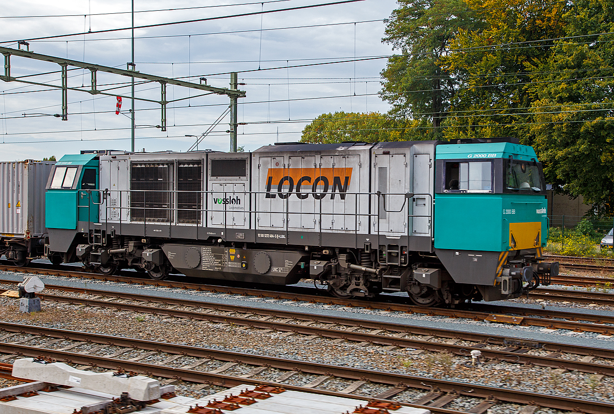 Die an die LOCON Benelux B.V. (Zwolle) vermietete 272 404-5 (92 80 1272 404-5 D-LBL) der Alpha Trains Belgium steht am 03.10.2015 mit einem Güterzug bei Sittard (NL). Bild aus dem Zug heraus. 

Die Vossloh G 2000-3 BB (mit symmetrisches Führerhaus) wurde 2005 von Vossloh in Kiel unter der Fabriknummer 5001605 gebaut. Sie hat die Zulassungen für Deutschland, die Niederlande und Belgien.

Die Lokomotive Vossloh G 2000 BB ist die stärkste dieselhydraulische Lokomotive der Vossloh Locomotives GmbH und wird seit dem Jahr 2000 gebaut. Ihre Achsfolge ist B’B’. Sie hat eine Leistung von bis zu 2.700 kW und erreicht je nach Motorisierung eine maximale Geschwindigkeit von bis zu 140 km/h. Je nach Ausrüstungsvariante bringt sie es auf ein Dienstgewicht von 84 t bis 90 t. Dabei erreicht sie eine Anfahrzugkraft von 283 kN bei 87,3 t. Das Tankvolumen beträgt 5000 l. Insgesamt gibt es 99 Loks der Typen 1–3 und je eine Lok der Typen 4 und 5. 

War das breitere Führerhaus zunächst nur für die italienische Ausführung wegen des dort vorgeschriebenen Beimannes und der dort üblichen Linkssteuerung gedacht, wurde es auch bei der dritten Version für den Verkehr in Deutschland, Niederlande, Belgien und Frankreich beibehalten, allerdings mit Steuerplatz auf der rechten Seite. Bei der ersten Serie befindet sich der Steuerplatz in der Mitte.

Die Lokomotiven haben einen tragenden Rahmen mit angesetzten Frontschilden als Kollisionsschutz. An beiden Seiten gibt es einen Endführerstand, entweder asymmetrisch, mit einem leicht gewendelten Einstieg (Typ 1) oder (wie hier) über die ganze Fahrzeugbreite. Zum Ende ist der Führerraum leicht eingezogen, auch ab Fensterunterkante wird er nach oben etwas schmaler. Der Zugang zum Führerstand erfolgt von hinten über den Umlauf. Der modular aufgebaute Maschinenraum geht nicht über die ganze Breite, so dass auf beiden Seiten Platz für einen Umlauf mit Geländer gibt. Es gibt fünf Module: Elektronik und Batterien, Kühlanlage mit seitlichen Kühlblöcken, Verbrennungsluftfilter (über dem Getriebe), Motor mit Abgasschalldämpfer und die Druckluftanlage. Im Bereich der beiden Kühlertürme sind an der Seite und im Dach große Lüftungsgitter, unterm Dach mit Lüftungsrotoren. Die Lok hält das niedrige Umgrenzungsprofil UIC 505-1 ein. Als Drehgestelle werden zweiachsige Flexicoil-Drehgestelle mit Radsatzlenkern verwendet, wie sie auch in den anderen Typen der „vierten Generation“ von Vossloh verwendet werden. Als Motor kommt in der Regel ein Viertakt-Motor Caterpillar 3616 B-HD mit 2.240 kW zum Einsatz. Aufgrund der hohen Leistung ist ein Einbau eines Turbowendegetriebes nicht möglich, so kommt ein hydraulisches Voith-Getriebe L 620 reU2 mit nachgeschaltetem mechanischen Wendegetriebe zum Einsatz, das nur im Stillstand betätigt werden kann.

TECHNISCHE DATEN:
Achsformel: B'B'
Spurweite: 1.435 mm (Normalspur)
Länge über Puffer: 17.400 mm
Drehzapfenabstand: 9.500 mm
Achsstand im Drehgestell: 2.400 mm
Treibraddurchmesser:  1.000 mm
Höhe: 4.220 mm
Breite: 3.080 mm
Dieselmotor: Caterpillar V-16-Viertakt-Dieselmotor mit Turboaufladung und Ladeluftkühlung vom Typ CAD 3516 B-HD
Motorleistung: 2.240 kW
Motor-Nenndrehzahl:  1800/min
Getriebe: Voith L 620 reU2
Leistungsübertragung: hydraulisch
Anfahrzugkraft:  283 kN
Dienstgewicht: 87,3 t
Höchstgeschwindigkeit: 120 km/h
Kleinster bef. Halbmesser: 80 m
Bremse: KE-GP
Tankinhalt: 5.000 l