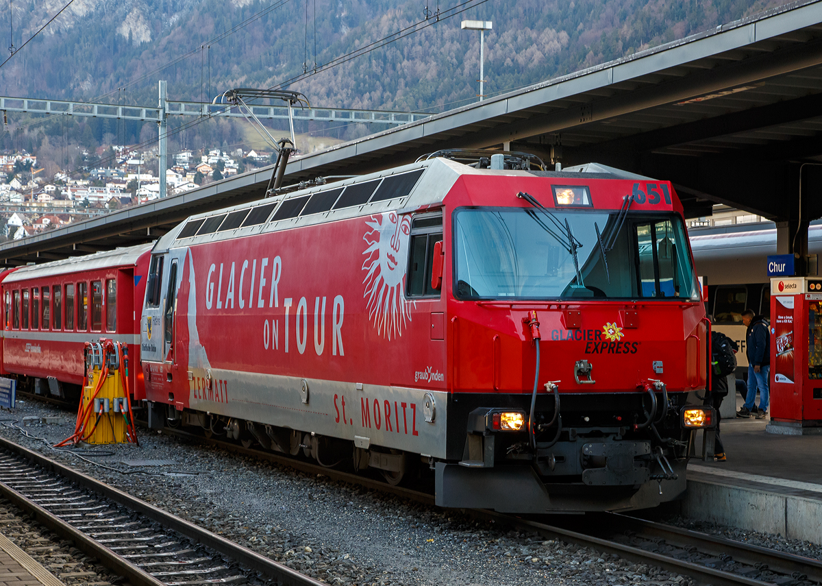 Die RhB Ge 4/4 III – 651  Fideris  mit Werbung fr den Glacier Express ( Glacier on Tour“) steht am 18.02.2017 im Bahnhof Chur mit dem RegioExpress nach St. Moritz zur Abfahrt bereit. Wir fuhren bis Samedan mit, aber zuvor musste ich schnell noch dieses Bild machen.

Durch das ansteigende Verkehrsaufkommen war die Rhtische Bahn (RhB) veranlasst Ende der 1980er Jahre ein Konzept fr eine neue Lokomotivgeneration zu erstellen. Gemeinsam mit SLM und ABB entwickelte die Rhtische Bahn eine Lok, deren Antrieb auf der Drehstromtechnik mit GTO-Thyristoren basiert. Die neuen Lokomotiven sollten in der Lage sein, Personen- und Gterzge auf dem Stammnetz, aber auch Autotransportzge durch den neuen Vereinatunnel zu ziehen. Wobei fr den Einsatz im Vereinatunnel eine sechsachsige Lok die ideale Wahl gewesen wre, wurde entschieden, vierachsige Fahrzeuge zu bestellen. Da die vierachsigen Loks fr die Fhrung von Zgen auf den kurvenreichen Strecken des Stammnetzes, wie beispielsweise der Albulalinie, geeigneter sind.

Neben den modernen GTO-Stromrichtern haben die Lokomotiven neu entwickelte Drehgestelle mit selbstndig radial einstellenden Radstzen, dadurch wird der Verschlei zwischen Rad und Schiene vermindert.

1989 bestellte die RhB sechs und 1991 weitere drei Lokn bei der Schweizer Industrie. Die Biere - Apples - Morges Bahn (BAM) schloss sich 1990 dieser Bestellung mit zwei Fahrzeugen fr die Befrderung schwerer Panzerzge an. Vier weitere Lokomotiven wurden unter Verwendung hnlicher mechanischer Komponenten fr die MOB gebaut. Der elektrische Teil der MOB Lokomotiven hingegen ist eine komplette Neuentwicklung. Pnktlich zur Erffnung des Vereina-Tunnels wurden von der RhB Ende 1999 drei weitere Lokomotiven in Betrieb genommen. 

Ein modernes und funktionelles Design wurde fr die Gestaltung von dem Lokomotivkasten gewhlt. Die Antriebseinheit besteht aus zwei modular aufgebauten, je einem Drehgestell zugeordneten, Zweipunkt-GTO-Umrichtern. Der Antriebsstromrichter eines Drehgestells speist zwei parallel geschaltete sechspolige Drehstrom-Asynchrontraktionsmotoren mit Kurzschlusslufer. Der unterflur angeordnete Transformator und die Wechselrichter sind lgekhlt. Die Leitelektronik wurde von der SBB Re 460 (Lok 2000) abgeleitet und basiert auf dem MICAS-S2 Leitsystem von ABB (spter Adtranz, jetzt Bombardier Transportation).

Fr die Bedienung des Fahrzeuges wurde von der RhB ein vllig neues Konzept gewhlt: die Vorgabe der Zug- und Bremskrfte erfolgt ber zwei Side-Sticks. Alle wichtigen Messwerte wie Fahrgeschwindigkeit, Zug-/Bremskraft, Fahrleitungsspannung und Bremsleitungsdruck werden auf zwei Displays angezeigt. Diese dienen auch zur Darstellung von Strungsmeldungen - konventionelle Messinstrumente sucht man in dem Fhrerraum vergeblich. Dieses Konzept konnte sich im Betriebsalltag nicht bewhren. Die 1999 gelieferten Lokomotiven Ge 4/4 III 650 - 652 (wie diese hier) wurden daher mit einem konventionellen Fahrerpult mit Handrad ausgestattet.

Die Mehrzwecklokomotiven des Typs Ge 4/4 III werden hauptschlich im Schnellzugdienst auf der Strecke Chur - St. Moritz sowie zur Befrderung der Autozge durch den Vereinatunnel eingesetzt. 

Technische Daten  der Ge 4/4 III:
Betriebsnummern: 641 – 652
Anzahl Fahrzeuge: 12

Ge 4/4 III 641 - 649
Hersteller – mecha. Teil: SLM
Hersteller - Elektrik: ABB Verkehrssysteme AG

Ge 4/4 III 650 - 652
Hersteller – mecha. Teil der : Adtranz (ex. SLM)
Hersteller - Elektrik: Adtranz (ex. ABB)

Baujahre: 1993 (6 Stck), 1994 (3 Stck) und 1999 (3 Stck)

Spurweite: 1.000 mm
Achsanordnung: Bo'Bo'
Hchstgeschwindigkeit: 100 km/h
Lnge ber Puffer: 16.000 mm
Achsabstand im Drehgestell: 2.400 mm
Triebraddurchmesser (neu):	1.070 mm
Breite: 2.800 mm
Dienstgewicht: 62,0 t
Anhngelast bei 4,5% mit 50 km/h: 210 t
Anhngelast bei 3,5% mit 60 km/h: 290 t
Anhngelast bei 1,5% mit 78 km/h: 350 t
Fahrleitungsspannung: 11 kV, AC 16,7 Hz
Anzahl Fahrmotoren:	4 Stck vom Typ 6 FRA 5248)
Max. Leistung am Rad: 3.100 kW
Dauerleistung am Rad: 2.400 kW
Max. Zugkraft am Rad: 200 kN
Dauerzugkraft am Rad: 170 kN
Getriebebersetzung:	1 : 6,136
