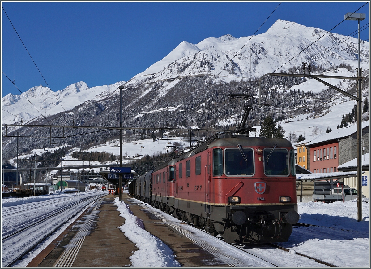 Eine  Re 10/10  mit der Re 4/4 II 11284 als Spitzenlok fährt in Airolo Richtung Süden. 
Im Hintergrund das Gotthard Massiv.
11. Feb. 2016