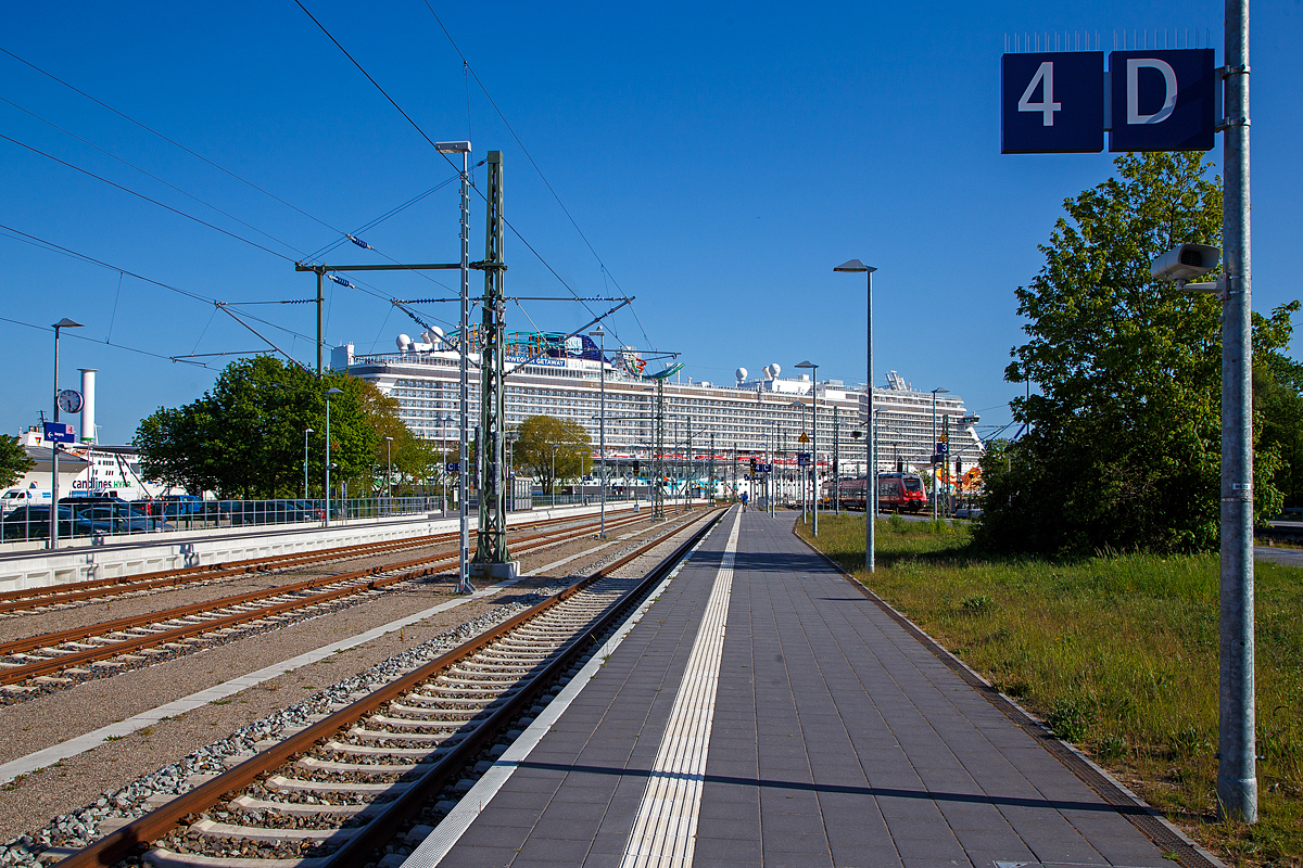 Mehr Schiffs- als Bahnbild...
Der Bahnhof Warnemnde am 15.05.2022, Blickrichtung Warnemnder Passagierkai (Warnemnde Cruise Center), wo gerade die Norwegian Getaway der Norwegian Cruise Line liegt, da wirkt rechts auf Gleis 2 der einfahrende „Hamster“ (Bombardier Talent 2) der S-Bahn Rostock winzig. 

Der Bahnhof Warnemnde liegt im gleichnamigen Ostseebad, einem Ortsteil der Hansestadt Rostock. Er ist Endpunkt der Linien S1, S2 und S3 der S-Bahn Rostock. Neben dem Rostocker Hauptbahnhof ist er der zweite Fernverkehrsbahnhof Rostocks mit IC Verbindungen nach Dresden, Wien und Leipzig. Bis 1995 war er Ausgangspunkt der Fhren nach Gedser in Dnemark (die zwei Fhrbetten wurden J2014/2015 durch eine neue Uferbefestigung berbaut und dadurch beseitigt). Das Empfangsgebude und einige weitere Anlagen des Bahnhofs stehen unter Denkmalschutz.

Die mchtige Norwegian Getaway der Norwegian Cruise Line wurde von der MEYER WERFT GmbH in Papenburg (Deutschland) unter der Baunummer S.692 gebaut. Die Kiellegung war 30. Oktober 2012, der Stapellauf am 2. November 2013, die Taufe 7. Februar 2014 und am 10. Januar 2014 erfolgte die bernahme durch die Reederei Norwegian Cruise Line. Das Schifft fhrt unter der Flagge von den Bahamas.

Weitere Daten und Fakten der Norwegian Getaway:
Tonnage: 145.655 BRT
Lnge: 326 Meter
Breite: 52 Meter
Max Geschwindigkeit: 23 Knoten (42,5 km/h)
Anzahl Decks: 14
Passagiere: 3.963
Crewmitglieder: 1.646
Restaurants: 16
Maschinenleistung: 62.400 kW (84.840 PS) durch 4  MAN-Dieselgeneratoren (Dieselelektrischer Antrieb
Propeller: 2  Azipod (Propellergondel, auch Pod-Antrieb genannt)

Einfach ein riesiger Pott, da bleiben wir lieben auf den Schienen und machen eher eine Schienen-Kreuzfahrt. 

