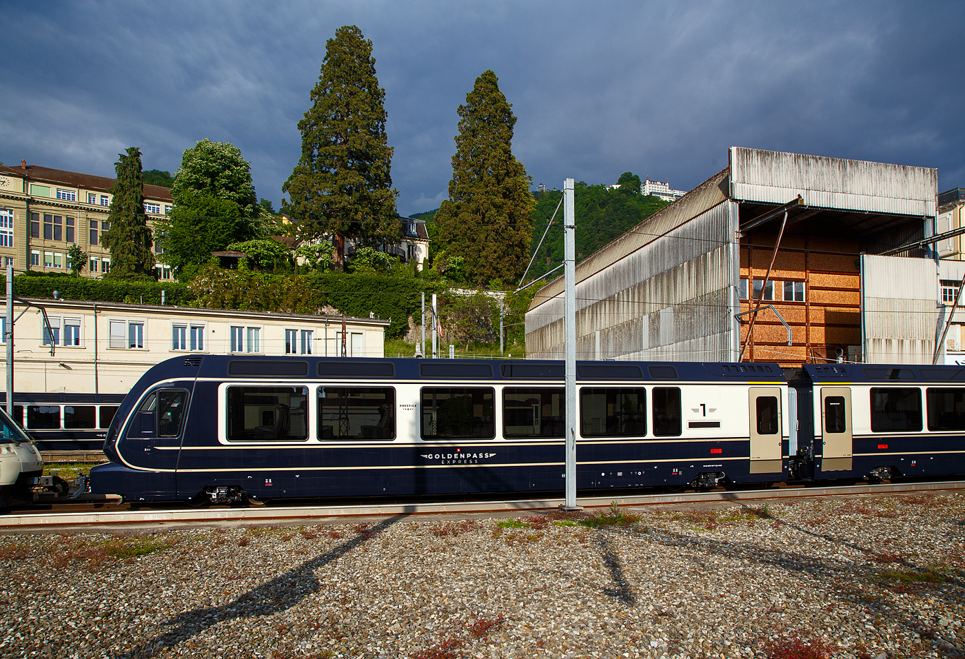 Der MOB GPX - GoldenPass Express Premium-/1.Klasse Steuerwagen Ast 183 (96 85 8300 183-7 CH-MOB) mit variablem Drehgestell (EV18) der Montreux-Berner Oberland-Bahn AG) abgestellt am 26. Mai 2023 beim Bahnhof Montreux. 

Diese Steuerwagen Ast 181 bis 184 (4 Stck), haben jeweils 9 Sitzpltze mit verstellbaren/drehbaren Sitzen in der Prestige Klasse und 20 Sitzpltze in der 1. Klasse. Die Wagenlnge ber die automatische Schwab-Kupplung betrgt 19.320 mm, das Eigengewicht eines Wagens betrgt 27,0 t.