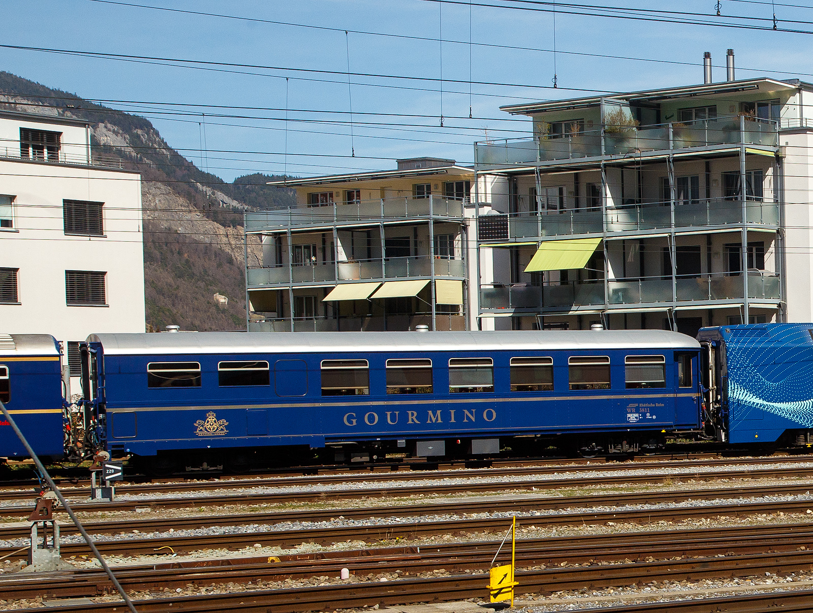 Der RhB Gourmino Speisewagen WR 3811, ex RhB Dr4 3811, ex Mitropa Dr4 11, am 22.03.2023 beim Bahnhof Chur abgestellt.

In den Jahren 1929 und 1930 beschaffte die Mitropa drei als Dr4 10-12 bezeichnete Speisewagen fr den Einsatz in den Luxuszgen der Rhtischen Bahn. Diese Fahrzeuge liefen nicht nur im Glacier Express, sondern auch im Engadin Express und auf Verbindungen nach Davos. Lieferant war die Schweizerische Waggons- und Aufzgefabrik Schlieren (SWS). 1949 ersteigerte die RhB die Speisewagen von der Mitropa.
Die Bezeichnung Dr4 10-12 wurde 1956 in Dr4 3810-3812 und spter in WR 3810-3812 gendert.

WR 3812 wurde 1974 versuchsweise modernisiert und mit Mikrowellenherden ausgerstet. WR 3810-3811 hingegen wurden 1982 bzw. 1983 als nostalgische Speisewagen hergerichtet und mit einer neuen Kcheneinrichtung versehen, die eine Zubereitung frischer Speisen gestattet.

1996 wurde WR 3812 generalberholt, wobei die RhB auch die Inneneinrichtung weitgehend in den Originalzustand zurckversetzte. Bei dieser Gelegenheit tauschte der Wagen sein rotes gegen ein knigsblaues Farbkleid mit groem  Gourmino -Schriftzug ein. Diesen aufflligen Farbton erhielten spter ebenfalls WR 3810-3811. Alle drei Wagen wurden inzwischen erneut umlackiert und prsentieren sich heute im noblen Blauton des Alpine Classic Pullman Express (ACPE). Der Gourmino fhrt meist auf der spektakulren Albulalinie zwischen Chur und St. Moritz.

TECHNISCHE DATEN:
Baujahr und Hersteller: 1929 / SWS
Spurweite: 1.000 mm
Anzahl der Achsen: 4
Lnge ber Puffer: 16.440 mm
Sitzpltze: 36
Eigengewicht: 25,0 t
zulssige Geschwindigkeit: 90 km/h
Lauffhig: StN (Stammnetz) / MGB (Matterhorn Gotthard Bahn)
