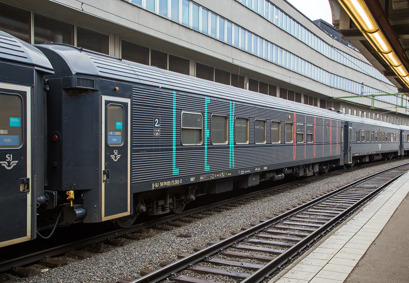 Der SJ Bistro- und Familienwagen 5301 der Gattung RB7, S-SJ 50 74 85-73 391-2, der SJ (Statens Jrnvgar AB, ehemaligen schwedische Staatsbahnen), ex SJ BFS9A 530, am 21 Mrz 2019 eingereiht in einem Personenzug nach Oslo im Bahnhof Stockholm Central (Stockholm Hbf). Der Wagen ist gekennzeichnet mit BISTRO und LEK (fr Spiel).

Ursprungswagen BFS9
Mitte der 1990er Jahre begann SJ mit dem Umbau von Waggons aus den 1980er Jahren im Rahmen des InterRegio-Konzepts, fr den Personenverkehr auf mittleren bis langen Strecken. InterRegio war eine Ergnzung zum InterCity-Verkehr auf lngeren Strecken. Die Ursprungswagen BFS9 waren 31 Wagen die zwischen 1994-1998 von Kalmar Verkstads AB in Verkstad, aus Wagen der Gattung A7 bzw. B7 (Bauart der 1980er Jahre), zu 2. Klasse Reisezugwagen mit Laderaum und Kiosk umgebaut wurden.

Die Wagen erhielten eine neue Innenausstattung mit Laderaum und Kiosk sowie eine neue Farbgebung mit einem breiten roten Zierstreifen entlang der Wagenseiten. SJ gab das InterRegio-Konzept nach einigen Jahren auf und die Wagen wurden in allen Zuggattungen eingesetzt.

Im Jahr 2012 beschloss die SJ dann 20 dieser BFS9-Wagen in Bistrowagen mit Sitzecke und Spielzimmer fr Kinder umzubauen. Der erste RB7-Wagen wurde im Juli 2013 fertiggestellt. Das Umbauprojekt wurde jedoch zu teuer und verzgerte sich so sehr, dass die Umbaufirma Motala Train AB finanzielle Probleme bekam und 2014 eine Unternehmensumstrukturierung durchfhren musste. Aus diesem Grund wurden allerdings nur sechs Wagen umgebaut. Zwei im Umbau befindliche Wagen wurden nie fertiggestellt, sondern spter verschrottet.

Auen erhielten die umgebauten Wagen nun die schwarze Lackierung von der SJ und Beschriftung BISTRO und LEK (fr Spiel). Der Bistrobereich erhielt auer dem Bereich mit regulren Sitzpltzen keine neuen eigenen Sitzpltze und kann daher eher als Kiosk betrachtet werden. Die RB7-Wagen sind teilweise ein Ersatz fr die frheren B8-Wagen, die auch ber einen Spielbereich verfgten. Die Wagen verfgen auerdem ber einen Rollstuhllift, Behindertenpltze und ein Serviceabteil fr das Zugpersonal. Die Wagen haben zudem Wifi und sind klimatisiert. 

TECHNISCHE DATEN:
Umgebaute Anzahl: 6
Nummerierungen SJ : 5213, 5220, 5229, 5301-5303
Hersteller / Umbauer: Kalmar Verkstads AB (Verkstad) / Motala Train AB
Umbaujahre: 2013-2015
Spurweite: 1.435 mm (Normalspur)
Lnge ber Puffer: 26.400 mm
Wagenkastenlnge: 25.900 mm
Wagenkastenbreite: 3.080 mm
Hhe ber Schienenoberkante: 4.400 mm
Drehzapfenabstand: 18.500 mm
Achsstand im Drehgestell: 2.500 mm
Laufraddurchmesser: 980 mm (neu)
Drehgestellbauart: MD 80-E (Minden-Deutz)
Leergewicht: 49 t
Hchstgeschwindigkeit: 160 km/h
Sitzpltze in der 2. Klasse: 41, sowie 3 Rollstuhlpltze
Toiletten: 2 (geschlossenes System)
Bremsbauart: KE-GPR

Quelle: jrnvg.net 
