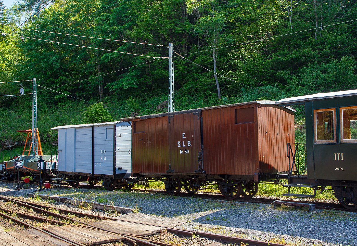 Der zweiachsige gedeckte Güterwagen K 30, ex S.L.B. E 30 (Schweizerische Lokalbahnen ab 1885 Appenzellerbahn-Gesellschaft, kurz Appenzeller Bahn), am 27.05.2023 im Museumsareal Chaulin der Museumsbahn Blonay-Chamby. 

Der Wagen wurde 1874 von der deutschen Maschinenfabrik Kirchheim an der Teck für Schweizerische Lokalbahnen S.L.B. gebaut. Er ist heute einer der ältesten in Europa.

Die 1872 gegründete Schweizerische Gesellschaft für Lokalbahnen war die Wiege der Appenzeller Bahn. Die SLB wollte viele Nebenstrecken in der Schweiz bauen, es zu viele Projekte. Sie baute die 1875 eröffnete Eisenbahnlinie zwischen Herisau und Winkeln im Kanton Appenzell (bis September 1875 bis Urnäsch verlängert), die nach der Lausanne-Echallens die zweite Schmalspurbahn in der Schweiz war. Durch die dauernde Finanzknappheit wurde die SLB 1875 umgewandelt und in Appenzeller Bahn-Gesellschaft, kurz Appenzeller Bahn, umbenannt. Die Appenzeller Bahn konnte im August 1886 die Weiterführung der Strecke zwischen Urnäsch und Appenzell in Betrieb nehmen, womit die konzessionierte Strecke vollendet war.

Lebenslauf des K 30 (E 30):
1874 Lieferung und Inbetriebnahme für Arbeits- und Güterzügen
1875 Offizielle Inbetriebnahme als S.L.B. E 30
1885 Aufgrund von miserablen Zustands war bereit der Abbruch geplant, die Tragfähigkeit wurde aber erstmal reduziert. 
1887 Überholungsarbeiten, Verstärkung des Rahmens, Erneuerung des Dachs und der Wagenkasten wurden restauriert. 
1898 Installation einer weißen Westinghouse-Bremsleitung
1900 Rekonstruktion des Fahrgestells und vollständige Überholung des Wagenkastens, Verstärkung durch Stahlplatten.
1923 Abstellung (aus aktivem Konto entfernt). 
1941 Reaktivierung des Wagens al AB K 47
1948 als AB K 147 neu nummerieren
1953 Überholung, Anstrich in grau
1963 Stilllegung, Reserve Herisau
1968 Der Wagen wird durch Beschluss der Generalversammlung der AB an Chemin de Fer Blonay-Chamby übertragen, die dann 1972 erfolgt.
Ob da wirklich noch was an dem Wagen aus dem Jahr 1874 stammt, kann ich bei dem Lebenslauf nicht sagen.

TECHNISCHE DATEN:
Baujahr: 1874
Hersteller: Maschinenfabrik Kirchheim an der Teck
Spurweite: 1.000 mm (Meterspur)
Achsanzahl: 2
Länge über Puffer: 6.600 mm
Achsabstand: 2.300 mm
Eigengewicht: 4,3 t
Nutzlast: 6 t

Dahinter steht der zweiachsige gedeckte Güterwagen ex LLB K 41.

