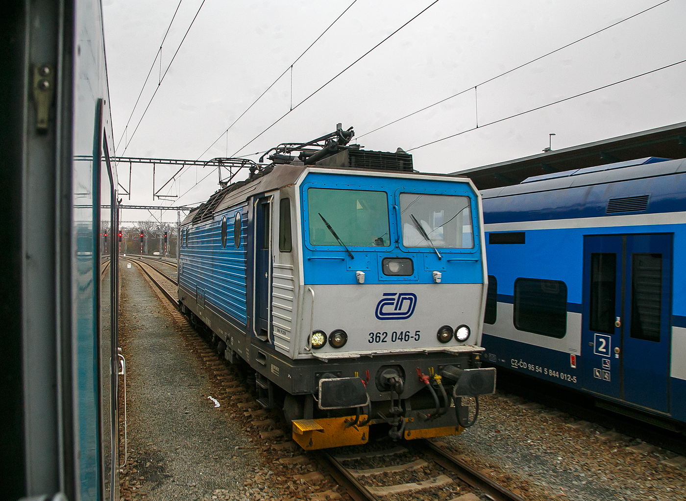 Die ČD 362 046-5 (CZ-ČD 91 54 7 362 046-5) der České dráhy (Tschechische Bahnen) rangiert am 22.11.2022 im Hauptbahnhof Pilsen (Plzeň hlavní nádraží), Zuvor hatte sie einen EX-Zug nach München (alex RE 25) von Prag nach Pilsen gezogen, ab hier dann die alexa 223 065 den Zug übernommen und zieht diesen bis Regensburg, wo wiederum eine 183er den Zug übernimmt.

Die Baureihe ČD 362 entstand aus Umbauten der 1984 bis 1990 von Škoda in Plzeň (Typ Škoda 69E) gebauten ČSD Baureihe ES 499.1 (ab 1988 BR 363). Die Loks sind elektrische Zweisystemlokomotiven für den universellen Einsatz. Sie sind sowohl im 3-kV-Gleichstromsystem im Norden und Osten wie auch im 25-kV-Wechselstromsystem im Westen und Süden der ehemaligen Tschechoslowakei einsetzbar.

Bereits 1990 wurde als Baureihe 362 erstmals eine 140 km/h schnelle Weiterentwicklung der ES 499.1/363 vorgestellt, wegen finanzieller Schwierigkeiten wurde auf eine Bestellung verzichtet. So wurden in den Jahren 1993/1994 und 2000/2001 Loks der BR 363 durch Anhebung der Höchstgeschwindigkeit von 120 auf 140 km/h zur BR 362 umgebaut. Dafür wurden die Drehgestelle mit solchen der Baureihe 162 ausgetauscht.

TECHNISCHE DATEN:
Spurweite: 1.435 mm (Normalspur)
Achsformel: Bo’Bo’
Länge über Puffer:  16.800 mm
Höhe:  4.625 mm
Breite:  2.940 mm
Drehzapfenabstand:  8.300 mm
Dienstgewicht:  87 t
Höchstgeschwindigkeit:  140 km/h
Dauerleistung:  3.060 kW (25 kV~) / 3.480 kW (3 kV=)
Anfahrzugkraft:  258 kN
Stromsystem:  3 kV DC und 25 kV 50Hz AC
Anzahl der Fahrmotoren:  4 (Typ Al 4542 FiR)
Antrieb:  Škoda-Hohlwellenantrieb
Zugheizung:  3000 V
Steuerung:  Thyristor-Pulsumrichter
Kupplungstyp:  Schraubenkupplung