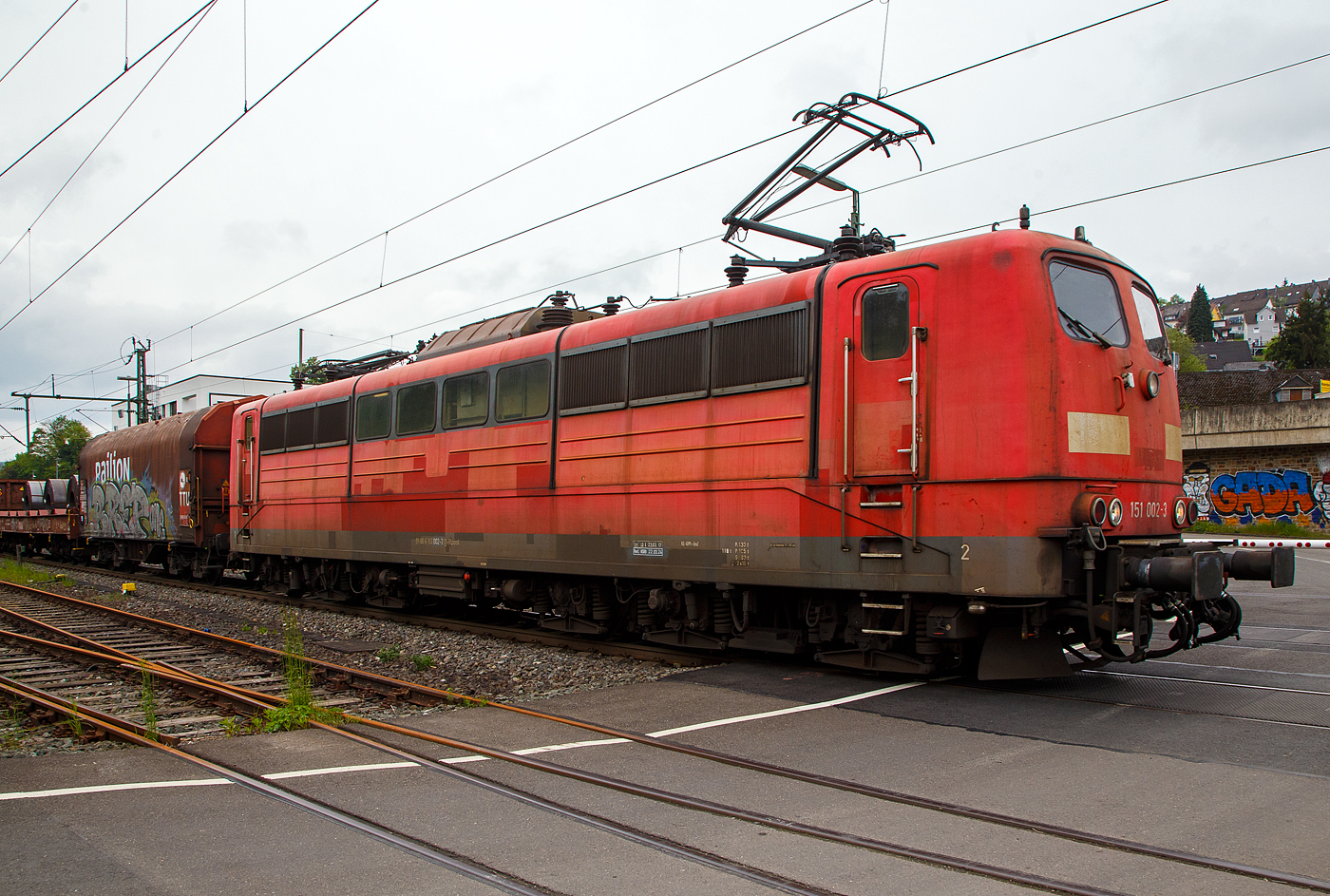 Die an die DB Cargo AG vermietete Railpool 151 002-3 (91 80 6151 002-3 D- Rpool) fhrt mit einem gemischten Gterzug am 11.05.2023 durch Niederschelden (hier beim B 343 – km 112,183 der Siegstrecke) in Richtung Siegen.

Die Lok wurde 1973 von Krupp in Essen unter der Fabriknummer 5174, der elektrische Teil ist von AEG unter Fabriknummer 8820, gebaut, und an die Deutsche Bundesbahn geliefert. Bis zum 31.12.2016 gehrte sie zur DB Cargo AG. Zum 01.01.2017 wurden je 100 sechsachsige elektrische Altbau-Lokomotiven der Baureihen 151 und 155 an ein Konsortium aus dem Lokvermieter Railpool verkauft. Die DB Cargo mietet daraufhin 100 Loks von Railpool wieder an. Die anderen Maschinen werden dem freien Markt angeboten.

Diese sechsachsigen Loks (Co’Co’) sind immer noch starke Zugpferde, und so manche moderne Lok hat nicht diese Leistungsfhigkeit. Mit einer Stundenleistung von 6.288 kW (8.550 PS) bei 92 km/h und einer Anfahrzugkraft von 395 kN knnen diese Loks 3.000 t Zge bei 3 ‰ Steigung noch mit einer Dauergeschwindigkeit 75 km/h ziehen, bei 2.000 t Zgen sind es 100 km/h.