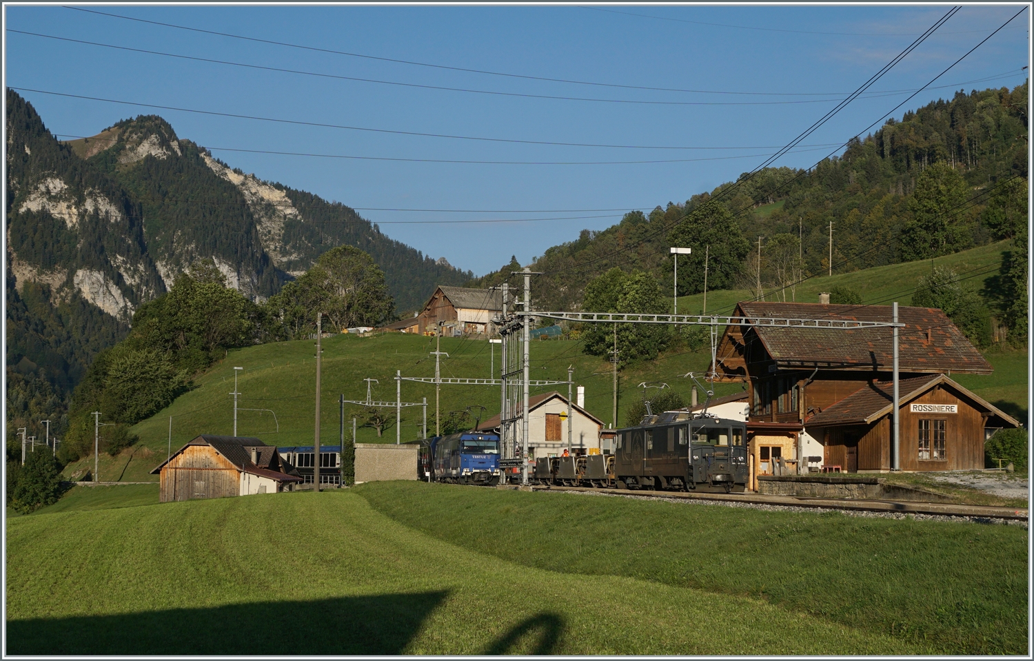 Die MOB Ge 4/4 8001 erreicht mit ihrem GoldenPass Express GPX 4064 von Montreux nach Interlaken Ost den Bahnhof von Rossinière. Und fährt auf Gleis 3 druch den Bahnhof, während auf Gleis 2 die GDe 4/4 6002 mit ihrem Güterzug auf die Weiterfahrt in Richtung Montreux wartet. 

29. Sept. 2023