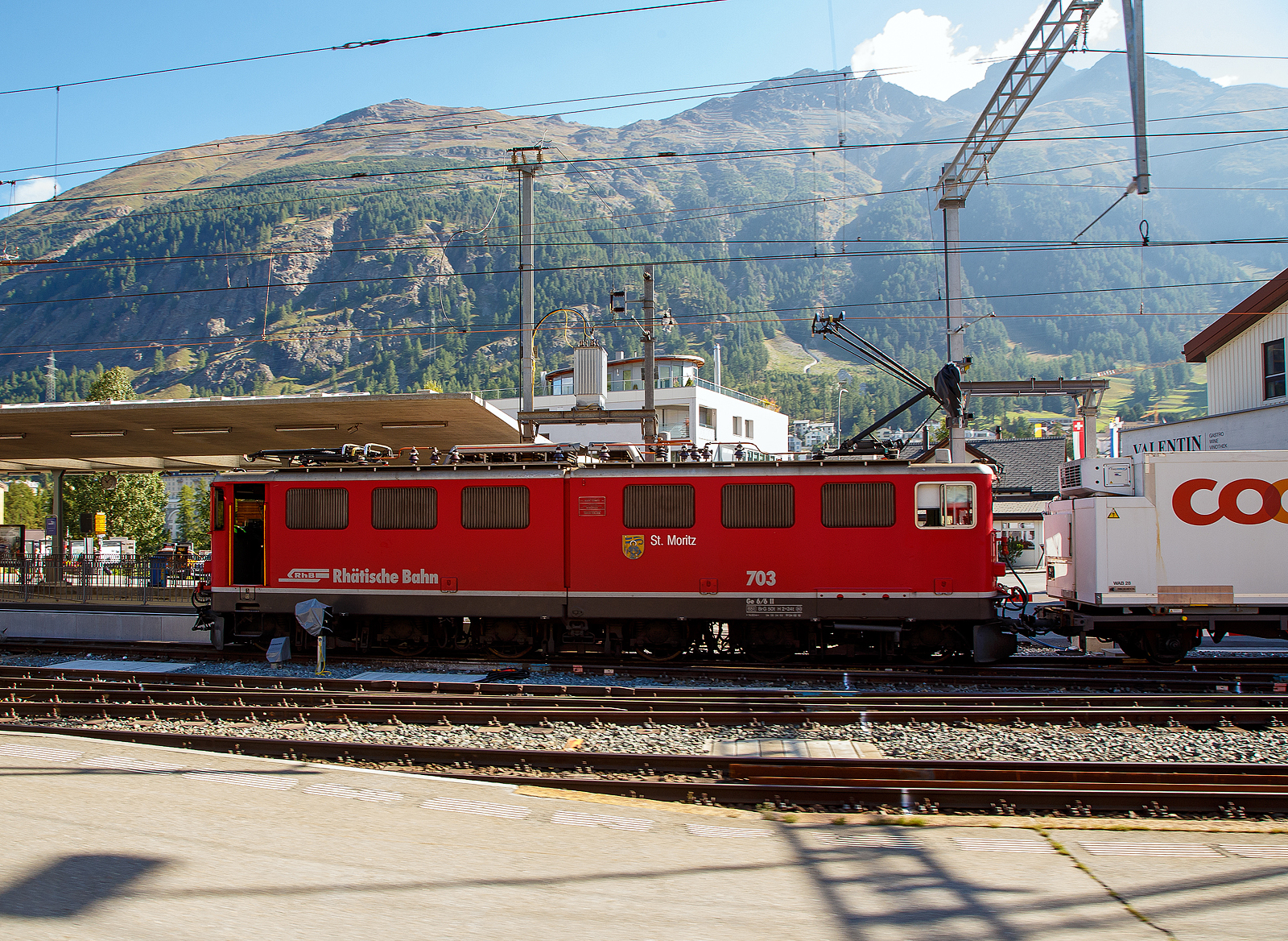 Die RhB Ge 6/6 II - 703 „St. Moritz“ steht am 06.09.2021 mit einem Gterzug im Bahnhof Samedan. Leider ist die RhB Ge 6/6 II – 703 auch schon Geschichte, sie wurde am 14. Juni 2022 in Chur abgebrochen (verschrottet). Auch zwei weitere (701 und 704) wurden bereits abgebrochen, die anderen vier Loks sind ausrangiert und wurden abgestellt. Nur die 707 „Scuol“ ist als historische Lok vorgesehen und z.Z. in Samedan abgestellt.

Die Ge 6/6 II ist/war eine schwere Elektrolokomotive der Rhtischen Bahn (RhB). Die sechsachsigen Maschinen (Achsformel Bo'Bo'Bo') wurden meistens im Gterzugdienst eingesetzt.

Zur Verstrkung des Lokomotivparks bestellte die RhB Mitte der 50er Jahre des vergangenen Jahrhunderts bei der schweizerischen Industrie eine leistungsstarke sechsachsige Gelenklokomotive. Zahlreiche Komponenten dieser Fahrzeuge mit geteiltem Lokomotivkasten wurden von der Ge 4/4 I bernommen. Mitte 1958 erfolgte die Auslieferung der ersten beiden Prototypen. Die folgende Serie von fnf weiteren Fahrzeugen wurde 1965, mit leicht genderter Front ohne bergangstr, ausgefhrt. Diese wurde bei den beiden Prototypen 1968/69 zugeschweit. Ein Umbau der Front entsprechend der Serie 703 - 707 erfolgte jedoch erst Ende der 80er Jahre. Ab 1985 wurden die ersten Maschinen umlackiert und trugen seitdem eine rote Lackierung. 1998 erfolgte, wie zuvor schon bei den Ge 4/4 I, ein Austausch der Scherenstromabnehmer durch moderne Einholmstromabnehmer.

ber weite Jahre wurden diese Fahrzeuge hauptschlich vor den Schnellzgen zwischen Chur und St. Moritz eingesetzt. Diese Aufgabe haben inzwischen die modernen Umrichterlokomotiven Ge 4/4 III bernommen. So sieht man sie heute meistens im Gterzugdienst.

Technisch entsprechen die Maschinen dem damaligen Stand: (Niederspannungs-) Stufenschalter und Einphasen-Reihenschlussmotoren. Die ueren beiden Drehgestelle und die Fahrmotoren knnen mit den Ge 4/4 I ausgetauscht werden. Das Kastengelenk zwischen den beiden Lokhlften erlaubt nur vertikale Bewegungen. 

TECHNISCHE DATEN:
Bezeichnung: Ge 6/6 II
Betriebsnummern: 701 – 707
Anzahl Fahrzeuge: 7
Baujahre: 1958 (701 und 702), 1965 (703 bis 707)
Hersteller Kasten und Drehgestelle: SLM
Hersteller Elektrik: BBC, MFO

Spurweite: 1.000 mm
Achsanordnung: Bo'Bo'Bo'
Lnge ber Puffer: 14.500 mm
Breite: 2.650 mm
Drehzapfenabstand: 8.600 mm (Der ueren Drehgestelle)
Gesamtradstand: 11.100 mm
Achsabstand im Drehgestell: 2.500 mm
Triebraddurchmesser (neu): 1.070 mm
Dienstgewicht:65,0 t
Hchstgeschwindigkeit: 80 km/h
Anhngelast: bei 45 ‰ 205 t / bei 35 ‰ 280 t
Fahrleitungsspannung: 11 kV, AC 16,7 Hz
Anzahl Fahrmotoren: 6 Stck (Typ 8SW570)
Max. Leistung am Rad: 1.776 kW (2.414 PS)
Max. Zugkraft am Rad: 213,9 kN
Dauerzugkraft am Rad: 135,4 kN
Getriebebersetzung: 1 : 5,437
