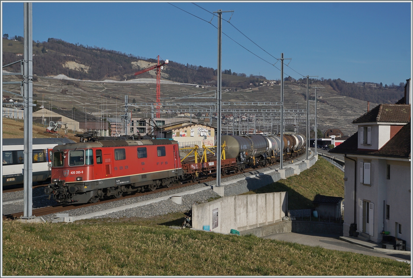 Die SBB Re 4/4 II 11285 (Re 420 285-9) ist mit einem Güterzug in Cully unterwegs und passt einigermassen zwischen die Fahrleitungsmasten. 

20. Februar 2023