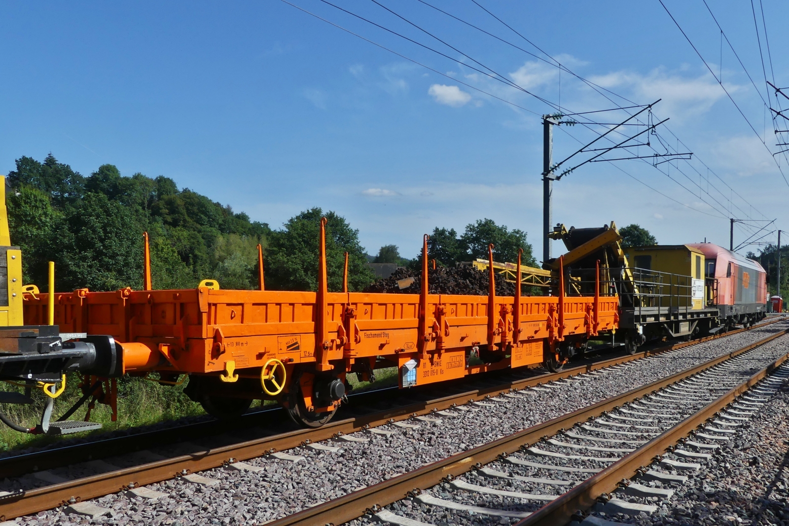 Flachgüterwagen der Reihe KS, (A-SWie 3312 015-9) beladen mit alten Schrauben und Schienenbefestigungen ist im Gleisbauzug bei Enscherange eingereiht. 23.08.2023