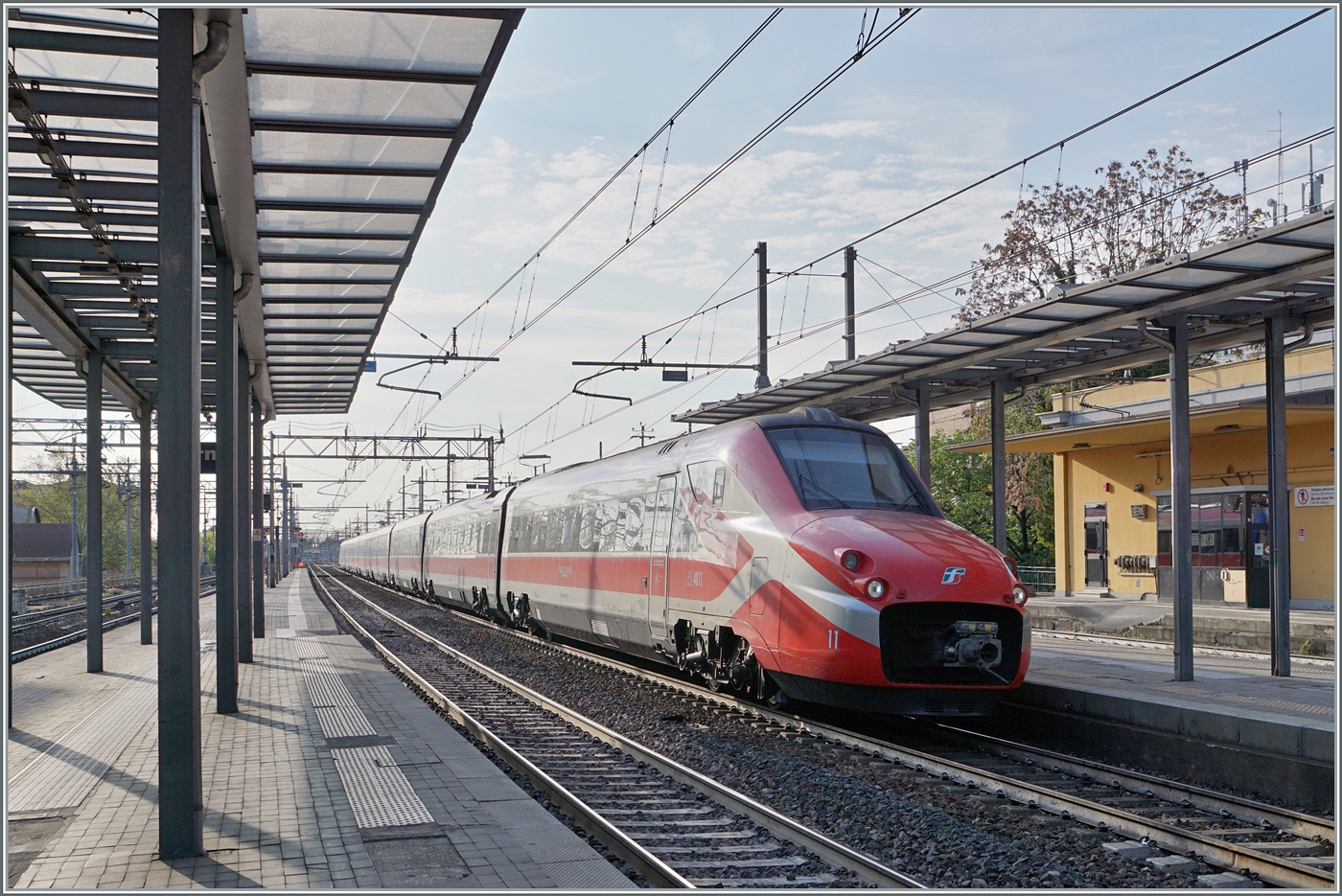 Im Gegenlicht erreicht der FS Trenitalia ETR 700 011 (ex Fyra) als Frecciarossa 8802 den Bahnhof von Parma. Der Zug ist von Ancona (ab 5:20) nach Milano (an 9:15) unterwegs und wird wie die meisten HGV-Züge der Relation Lecce - Milano erst nördlich von Fidenza auf die Schnellfahrstrecke geleitet.

18. April 2023
