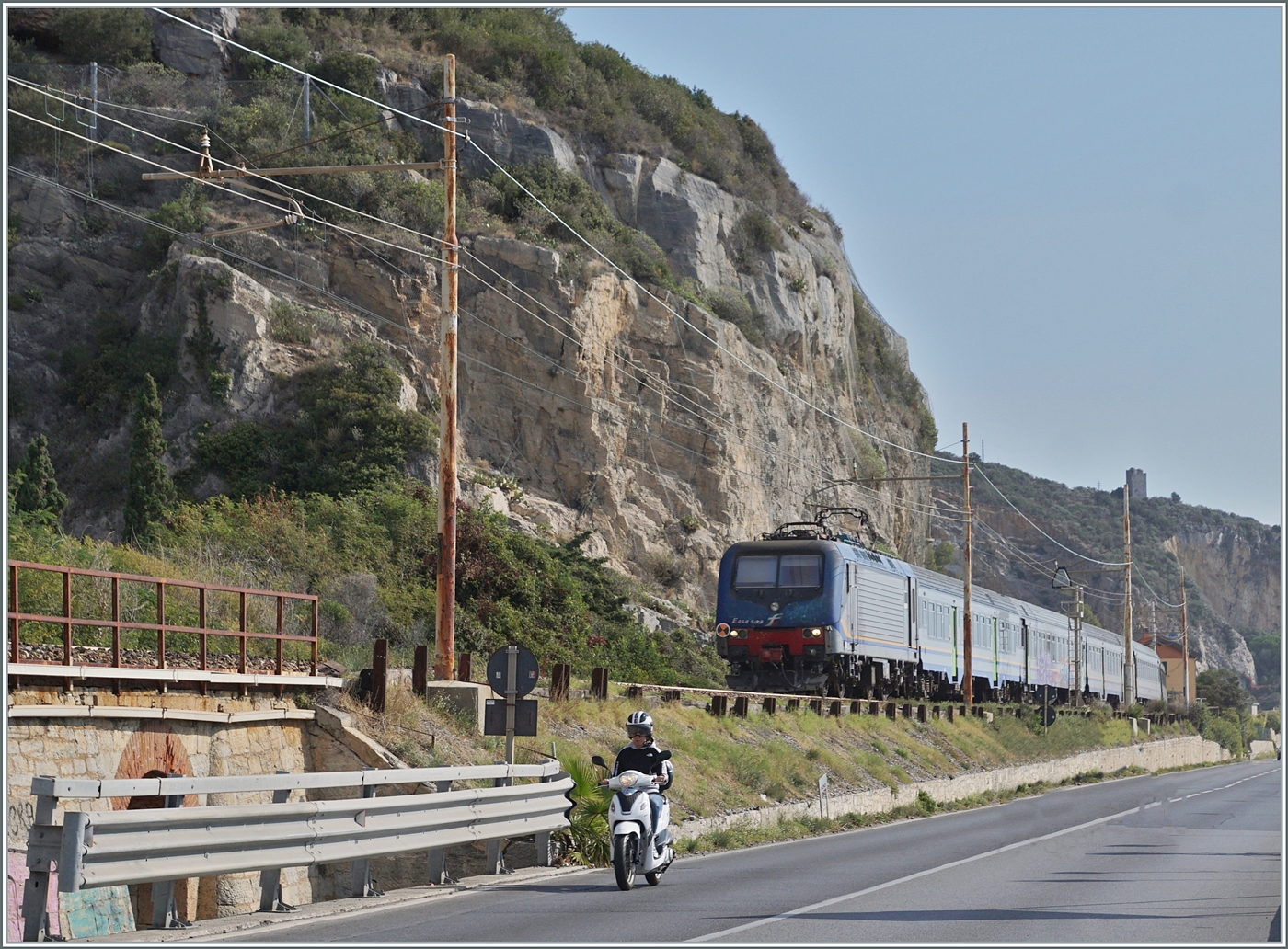 Typisch Italien, Bahn und Strasse teilen sich den engen Raum zwischen den aufragenden Bergen und dem Mittelmeer. Das Bild entstand bei Finale Ligure, und  gerade auf dem Streckenabschnitt an der Riviera dei Fiori verschwanden betrchtliche Streckenabschnitte in Tunnel, so dass das die typische Italienische Bahnambiente schon fast die Ausnahme darstellt. 

Die FS Trenitalia E 464 509 ist mit einem Regionalzug auf dem Weg nach Ventimiglia. 

22. Sept. 2022