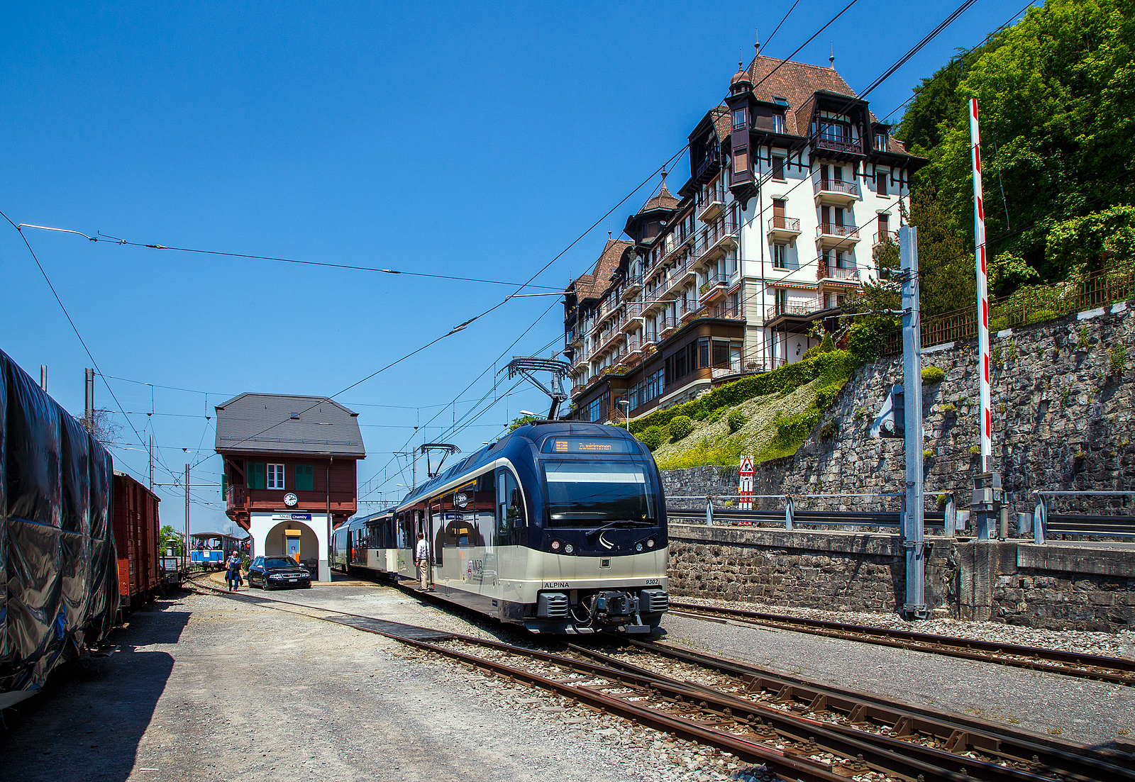 Über dem Genfersee, der Bahnhof Chamby am 27.05.2023.

Der Bahnhof Chamby ist ein Keilbahnhof, und liegt an der MOB (Montreux–Berner Oberland-Bahn) Strecke (KBS 120) Montreux–Montbovon–Zweisimmen, von hier zweigt die Strecke (KBS 115) nach Blonay ab, diese wird in der Sommersaison von der Museumsbahn Blonay–Chamby, gehört aber der Transports Montreux–Vevey–Riviera (MVR, ex CEV). Neben dem Bahnhofsgebäude der MOB befindet sich hier auch ein Ticketschalter der Museumsbahn BC.

Hier im Bild in Blickrichtung Blonay, von links nach rechts, ein Zug der Museumsbahn BC, das MOB Bahnhofsgebäude und MOB Regionalzug (R 2220 von Montreux nach Zweisimmen) am Zugschluss mit dem MOB ALPINA ABe 4/4 9302 „Chateau-d'Oex“. 
