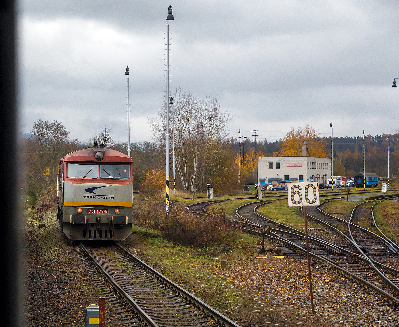 Wir erreichen am 24.11.2022 mit dem EC 360 / Ex 6 (Praha – Plzeň - Furth i.W. - Schwandorf – Regensburg – Mnchen) nun den Bahnhof Domalice (Taus) an der „Bhmische Westbahn“ Bahnstrecke Plzeň–Furth im Wald (SDC 180), whrend rechts die ZSSK Cargo 751 173-6 als Lz ber die Bahnstrecke Janovice nad hlavou–Domalice (SDC 185) ankommt.  

Die Kursbuchstrecke SDC 185 von Janovice nad hlavou nach Domalice (deutsch Janowitz an der Angel – Taus) ist Teil der ehemaligen Bhmisch-Mhrische Transversalbahn der ehemaligen k.k. sterreichischen Staatsbahn (kkStB), sie verlief von der damaligen ungarischen Grenze am Vlarapass bei Uhersk Hraditě (Hradisch) nach Domalice (Taus) und hatte dort Anschluss an bayerische Strecken.

Die ZSSK Cargo 751 173-6, ex ČSD-Baureihe T 478.1, ist eine dieselelektrische Universallokomotive der ehemaligen Tschechoslowakischen Staatsbahnen (ČSD). Die Lokomotiven prgten ab den 1960er Jahren den Streckendienst auf nichtelektrifizierten Strecken der ČSD und galten auf Grund ihrer Zuverlssigkeit als eine der erfolgreichsten Diesellokomotiven in der ehemaligen Tschechoslowakei. Unter Eisenbahnfreunden erfreuten sich die Maschinen, die auf Grund ihres markanten ueren den Spitznamen Bardotka (abgeleitet von Brigitte Bardot) oder Zamračen (Finstergesicht) erhielten. Zwischen 1966 und 1977 wurden von ČKD Praha 230 Loks als T 478.1 und 82 Loks als T 478.2 gebaut.
