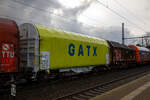 gatx-rail-germany-gmbh/798255/vierachsiger-drehgestell-flachwagen-mit-verschiebbarem-planenverdeck-und Vierachsiger Drehgestell-Flachwagen mit verschiebbarem Planenverdeck und Lademulden für Coiltransporte, 37 80 4668 599-6 D-GATED, der Gattung Shimmns-ttu, der GATX Rail Germany GmbH, am 07.12.2022 im Zugverband bei einer Zugdurchfahrt im Bahnhof Dresden-Strehlen. Der Waggonvermieter GATX (General American Transportation Corporation) ist eine US-amerikanische Leasinggesellschaft für Schienenfahrzeuge mit Sitz in Chicago. GATX wurde 1898 gegründet und ist seit 1916 an der New Yorker Börse notiert.

Diese Wagen sind speziell für den Transport witterungsempfindlicher Blechrollen (Coils) bestimmt. Er besitzt feste Stirnwände, 5 fest im Untergestell eingebaute Lademulden. Die Wagenabdeckung erfolgt mit einer PVC-beschichteten Gewebeplane, die auf 11 Rohrrahmen aufliegt. Über Laufwagen ist das Planendach in Wagenlängsrichtung verschiebbar. Die Verriegelung des Planendaches an den Stirnwänden erfolgt über eine 4-Punkt-Zentralverriegelung, die sowohl vom Erdboden als auch von der Rampe aus bedient werden kann. Das Planenverdeck lässt sich an einem Wagenende so weit zusammenschieben, dass ca. 2/3 der Ladefläche zur Beladung freigegeben wird. Hierdurch ist eine einfache Beladung des Wagens sowohl von oben als auch von der Seite aus möglich. 

TECHNISCHE DATEN:
Spurweite: 1.435 mm
Achsanzahl: 4 (in 2 Drehgestelle)
Länge über Puffer: 12.040 mm
Länge der Ladefläche: 10.800 mm
Drehzapfenabstand: 7.000 mm
Achsabstand im Drehgestell: 1.800 mm
Eigengewicht:  21.770 kg
Höchstgeschwindigkeit: 100  km/h (beladen) / 120 km/h (leer)
Maximales Ladegewicht: 68,2 t (Streckenklasse D4)
Kleinster bef. Gleisbogenradius: 35 m
Bauart der Bremse: KE-GP-A (K)
Bremssohle: C 810
Intern. Verwendungsfähigkeit: TEN - GE