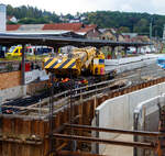 Hering Bau/897066/mal-ein-blick-ueber-den-teleskopausleger Mal ein Blick über den Teleskopausleger.  
Nun im Einsatz der 125 t KIROW Gleisbauschienenkran KIROW Multi Tasker KRC 810 T (mit Schwerlastausrüstung), Schweres Nebenfahrzeug Nr. D-HGUI 99 80 9419 024-1, ex 97 82 53 513 19-3, der HERING Bahnbau GmbH (Burbach) ist am 29 September 2025 im Betzdorf/Sieg. 

Hier im Bereich unter dem P+R Parkhaus bis zum Fluss Sieg werden Horizontalbohrungen gemacht, vermutlich für erforderliche Entwässerungs-Leitungen. So mussten Bohrrohre in die Baugrube gehoben werden und wie hier der Abraum aus der Baugrube gehoben werden. Eigentlich ist ein 125 t Kran damit unterfordert (überdimensioniert), aber man muss bedenken es wurde eine weite Auskragung (Ausladung vor Puffer) und das freistehend (Nichtabgestützt) benötigt. 

Der hier mit der Ausladung vor Puffer von über 15 m könnte der Kran freistehend 30 t heben, aber darf dann nicht schwenken. Wenn geschenkt werden muss liegt diese dann nur bei 1,5 t. Entscheidend für die Ausladung des Auslegers ist aber auch die hintere Ausladung des Gegengewichts