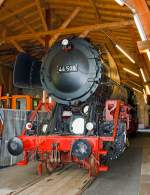 An dem Jumbo gibt es noch sehr viel Arbeit....

Die schwere Güterzug-Dampflokomotive 44 508, ex DB 044 508-0, am 18.05.2014 ausgestellt im Lokschuppen vom Erlebnisbahnhof Westerwald der Westerwälder Eisenbahnfreunde 44 508 e. V. hier war Museumstag. Die Lok ist Eigentum vom DB-Museum und eine Leihgabe an die Eisenbahnfreunde, die nach ihr ihren Verein genannt haben.

Die Dampflokomotive 44 508 wurde im Jahr 1941 von der Lokomotivfabrik Krauss-Maffei in München unter der Fabriknummer 16113 gebaut und an die DR geliefert. Nach dem Krieg blieb sie im Westen und wurde so 1949 als 44 508 in den Bestand der Deutsche Bundesbahn aufgenommen, mit der Einführung des EDV-Nummernschemas wurde sie zum 01.01.1968 in 044 508-0 umgezeichnet.
Bis zu ihrer Außerdienststellung im Jahre 1977 legte sie eine Strecke von über 1.9 Millionen Kilometern zurück.

Die Maschine verfügt über ein Drei-Zylinder-Triebwerk, fünf Antriebsachsen und einen Schlepptender, in dem sie 10 Tonnen Kohle und 34 Kubikmeter Wasser mitführen kann. Sie erreicht eine maximale Leistung von 1910 PS bei einem Dienstgewicht von 160 Tonnen. 

Die 44 508 wurde im Mai 1977 beim Bahnbetriebswerk Gelsenkirchen-Bismarck außer Dienst gestellt. Die 44 508 ist eine der letzten erhaltenen Dampflokomotiven ihrer Bauart. Sie wurde im Jahr 1987 durch eine Freizeitgruppe des Bahn-Sozialwerkes (BSW) übernommen. Damit begann die museale Aufarbeitung der Lok, die im Jahre 2002 jedoch unterbrochen wurde, als das Domizil in Siershahn geräumt werden musste. Der Verein Westerwälder Eisenbahnfreunde übernahm diese Dampflokomotive als Leihgabe des DB Museums, auch wenn sie nie im Westerwald eingesetzt war. 

Um das hohe ehrenamtliche Engagement und die damit verbundene immense Zahl von bereits geleisteten Arbeitsstunden zu würdigen, soll sie im Erlebnisbahnhof Westerwald weiterhin äußerlich aufgearbeitet werden und einen Ehrenplatz im Museum erhalten.


Die Lokomotiven der Baureihe 44 der Deutschen Reichsbahn waren schwere, fünffach gekuppelte Güterzug-Einheitsdampflokomotiven der Gattung G 56.20 mit Drillingstriebwerk. Sie waren vorgesehen für die Beförderung von Güterzügen bis 1.200 t auf Mittelgebirgsstrecken und 600 t über Steilrampen.

Im Jahr 1926 wurden 10 Prototypen gebaut, denen 1932 zwei weitere folgten. Die Serienfertigung der Baureihe 44 begann erst 1937, nachdem ihr Weiterbau anstelle der Zwei-Zylinder­Lokomotiven der Baureihe 43, die parallel zur 44 entwickelt und gebaut worden war, beschlossen wurde. Die Baureihe 44 wurde dagegen als Drei-Zylinder-Lokomotiven ausgebildet, wobei der dritte Zylinder im Rahmen unter der Rauchkammer angeordnet ist. Die großen Leistungsreserven und ihre ausgezeichnete Laufruhe wogen den Nachteil der schwierigen Unterhaltung des im Rahmen schlecht zugänglichen dritten Triebwerkes mehr als auf. So verwundert es nicht, dass die letzte Dampflokomotive, die bei der Deutschen Bundesbahn in Betrieb war, der Baureihe 44 angehörte. Es handelt sich um 44 903 Öl, die am 26.10.1977 in Emden außer Dienst gestellt wurde.


Technische Daten:
Gebaute Stückzahl: 1989
Bauart  1'E h3
Gattung:  G 56.20
Spurweite:  1435 mm (Normalspur)
Länge über Puffer:  22.620 mm
Höhe:  4.550 mm
Fester Radstand:  3.400 mm
Gesamtradstand:  9.650 mm
Dienstgewicht:  169,8 t (mit Tender)
Radsatzfahrmasse:  19,8 t
Höchstgeschwindigkeit: 80 km/h (rückwärts nur 50 km/h)
Leistung:  1.910 PS (1.405 kW) bei Lok mit Ölfeuerung 2.100 PS
Treibraddurchmesser:  1.400 mm
Laufraddurchmesser vorn:  8.50 mm
Zylinderanzahl:  3
Zylinderdurchmesser:  550 mm
Kolbenhub:  660 mm
Kesselüberdruck:  16 bar
Rostfläche:  4,55 m²
Überhitzerfläche:  100,00 m²
Verdampfungsheizfläche:  237,67 m²
Bremse:  selbsttätig wirkende Einkammerdruckluftbremse Bauart Knorr
Steuerung:  Bauart Heusinger

Tender: 2´2´T34
Kohlenvorrat:  10 t
Wasservorrat: 34 m3
