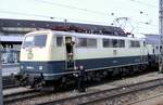 111 001-4 bei der Übergabe der Papiere; der Zug ist so lang, dass der Zugführer ins Schotterbett muss, München Hbf am 25.04.1982.