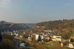 . Aussicht in der Stadt Luxemburg auf den Stadtteil Pfaffental (luxemburgisch: Pafendall) mit der Großherzogin-Charlotte-Brücke (luxemburgisch: Roud Bréck), die eines der Wahrzeichen der Stadt Luxemburg ist, und der Z 2 Dreifacheinheit, die als RB 3639 Diekirch - Luxembourg den Grünewald Viadukt (Länge: 70 m, Höhe: 15,2 m, 7 Bögen von 8 m Durchmesser) befährt. 23.03.2015 (Jeanny)
