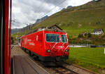 Wir sind am 07 September 2021 mit dem MGB Regionalzug von Andermatt nach Visp (auf der Furka-Oberalp-Bahn) unterwegs, in mssen wir Hospental (von lateinisch hospitale „Herberge“)  den Gegenzug abwarten. So kommt uns die MGB HGe 4/4 II 103 „Chur / Marcau da Cuera“ mit dem Glacier Express (Zug PE 902) entgegen.

Die HGe 4/4 II 103 „Chur / Marcau da Cuera“  wurde 1986 von der SLM (Schweizerische Lokomotiv- und Maschinenfabrik) in Winterthur unter der Fabriknummer 5292 gebaut und an die FO (Furka-Oberalp-Bahn) geliefert. Der elektrische Teil ist von BBC. Sie ist eine der 5 Prototypen Maschinen.

Die HGe 4/4 II ist eine schmalspurige (1.000 mm) gemischte Zahnrad- und Adhsions-Lokomotive. Eine erste Serie von fnf Lokomotiven wurde gemeinsam von der Furka-Oberalp-Bahn (FO) sowie von der SBB fr die Brnigbahn, die heute zur Zentralbahn (zb) gehrt, beschafft. Da sich dieser Lokomotivtyp bewhrte, wurden weitere elf Lokomotiven bestellt, und schlielich gab auch noch die Brig-Visp-Zermatt-Bahn (BVZ) fnf Loks in Auftrag.

Die HGe 4/4 II bespannt vor allem schwere Personenzge, zum Teil im Pendelzugbetrieb. Bei der Zentralbahn bespannte sie bis 2012 alle Schnellzge von Meiringen nach Luzern, bei der Matterhorn Gotthard Bahn die Zge des Glacier-Express. Weiter fhren die Loks Pendelzge Brig–Visp–Zermatt und seit der Erffnung des Tunnels nach Engelberg Pendelzge Luzern–Engelberg. Auerdem werden aushilfsweise Autopendelzge durch den Furkatunnel gefhrt. Schlielich gehren neben weiteren Personenzgen auch diverse Gterzge Visp–Zermatt sowie bis 2013 Disentis–Sedrun (NEAT-Baustelle) zum Aufgabengebiet.

Konstruktion:
Der Lokomotivkasten ist ein Stahlblechkasten mit gesickten Seitenwnden. Die asymmetrische Frontscheibe aus beheizbarem Verbundglas verbessert die Sicht fr den Lokomotivfhrer. Die drei Dachelemente sind aus Aluminium. Die Pufferkrfte werden ber Verstrebungen auf den ganzen Kasten bertragen, weshalb auf seitliche Maschinenraumffnungen verzichtet werden musste. Der gesamte Kasten hat ein Gesamtgewicht von nur 5,9 Tonnen. Er kann ohne bleibende Deformation eine zentrale Druckkraft von 1000 kN aufnehmen.

Die Drehgestelle sind als geschweite Hohltrgerkonstruktion mit zwei Lngstrgern und einem krftigen mittleren Quertrger sowie zwei Kopftraversen ausgefhrt. Sie haben einen Achsstand von 2980 mm, und die Flexicoil-Federn sttzen den Kasten auf die seitlich an die Lngstrger angeschweiten Federwannen. Die Zug- und Druckkrfte werden durch seitlich angeordnete Stangen mit Sphrolastiklagern bertragen. Wegen des kurzen Achsstands sind die Fahrmotoren oberhalb des Drehgestellrahmens angebracht.
Fr den Antrieb wurde erstmals der Differentialantrieb eingebaut, der es ermglicht, im Zahnstangenbetrieb auch einen Anteil der Zugkraft ber den Adhsionsantrieb aufzubringen. Dies setzt wiederum eine Schlupfbegrenzung im Differentialgetriebe voraus, um ein Schleudern oder Gleiten der Rder zu verhindern. Da die zweilamellige Abtzahnstange (System Abt) der FO nicht die gesamte Zugkraft aufnehmen kann, ist die Mithilfe des Adhsionsantriebs notwendig; dieser bernimmt einen Drittel der Zugkraft. Htte sich der Antrieb nicht bewhrt, wre es zumindest am Brnig mit der Riggenbachzahnstange mglich gewesen, auf einen abkuppelbaren Adhsionsantrieb zu wechseln. Dies war aber nicht notwendig, da das Differentialgetriebe zur vollen Zufriedenheit funktionierte.

Bremssysteme:
Dank der elektrischen Rekuperationsbremse ist eine gleichmige Beharrungsbremse bei der Talfahrt mglich.
Daneben ist eine normale automatische Druckluftbremse eingebaut, welche auch als Bremssystem I bezeichnet und im Regelbetrieb zum Halten des Zuges verwendet wird. Sie ist als Klotzbremse ausgefhrt.
Weiterhin ist noch das Bremssystem II installiert, welches fr Zahnradbahnen vorgeschrieben ist und es ermglichen soll, den Zug nur mit Hilfe der Lokomotive im Zahnstangenabschnitt zum Halten zu bringen, wenn das erste Bremssystem ausfallen sollte. Dieses ist als federspeichergesttztes Bandbremssystem ausgelegt, welches direkt auf das Zahnrad wirkt. Bei Einsatz dieser Bremse treten enorme Krfte auf, welche nur unter Kontrolle sind, wenn die Anhngelast bei der Talfahrt nicht zu gro ist.
Schlielich ist eine direkt wirkende Rangierbremse vorhanden, die sich der Bremskltze des Bremssystems I bedient.
Die Lokomotive hat keine Handbremse, sondern wird mit Federspeicherbremsen gesichert.

TECHNISCHE DATEN der HGe 4/4 II der FO und BVZ (heute MGB), 
die Daten der  zb (Zentralbahn), ex SBB Brnigbahn weichen ab:
Spurweite: 1.000 mm
Achsformel: Bo'Bo'
Dienstgewicht: 64 t 
Achslast: 16 t
Lnge ber Puffer: 14'.776 mm 
Hchstgeschwindigkeit Adhsion: 100 km/h
Hchstgeschwindigkeit Zahnrad: 40 km/h
Stromsystem: 11 kV 16.7 Hz
Anzahl der Motoren: 4
Adhsions-Antrieb: Gelenkwelle
Antrieb Zahnrad: Differentialantrieb
Zahnradsystem:  Abt (zweilamellig)
Stundenleistung: 1.932 kW
Dauerleistung: 1.875 kW
Anfahrzugkraft: 230 kN (Adhsion) / 280 kN (Zahnrad)
Anzahl Bremssysteme: 4
Bremsen: Rekuperation, Klotz, Federspeicher, Bandbremse
Anhngelast: 130 t (125 ‰)