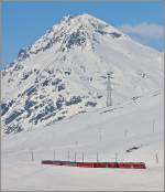 Ein Zug der Berninabahn auf der Bergfahrt in Richtung Ospizio Bernina vor der Kulisse des Piz Alv.