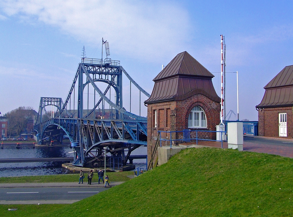 Die Kaiser-Wilhelm-Br�cke in Wilhelmshaven am 16.04.2006. Sie ist eine symmetrische, zweifl�gelige Stra�en-Dreh-Br�cke aus genietetem Stahlfachwerk und das Wahrzeichen von Wilhelmshaven. Sie hat eine Spannweite von 159 Metern, eine Breite von acht Metern und dient - bis heute - als Verbindung zwischen der S�dstadt und der S�dstrandpromenade. Die Durchfahrtsh�he betr�gt 9 m, die Durchfahrtsbreite 58 m. Damit ist sie die gr��te deutsche Drehbr�cke geblieben. Die st�hlernen Fl�gel der Kaiser-Wilhelm-Br�cke bewegen sich unabh�ngig voneinander und wurden urspr�nglich durch getrennte Fahrst�nde in den Br�ckenh�usern gesteuert. Seit 1995 sind sie durch eine Person zentral zu bedienen. 
