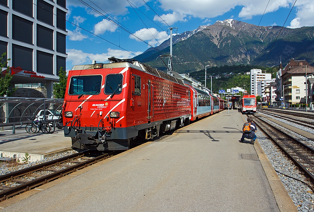 Ein Fotograf und die MGB (Matterhorn Gotthard Bahn)....:-)
Hier am 28.05.2012 in Brig am Bahnhofsvorplatz.
Links steht die MGB HGe 4/4 II - 3   Dom  (ex BVZ 3   Dom ) mit dem Glacier Express. Die HGe 4/4 II ist eine schmalspurige gemischte Zahnrad- und Adhsions-Lokomotive.
Rechts im Fokus des Fotografen ist der MGB Niederflur-Panoramatriebzug  Stadler - KOMET ABDeh 4/10 2012. Ein Schmalspur-Triebzug mit gemischten Zahnrad- und Adhsionsantrieb. Die Hchstgeschwindigkeit des KOMET betrgt 80 km/h (Adhsion) bzw. 40 km/h (Zahnrad).
