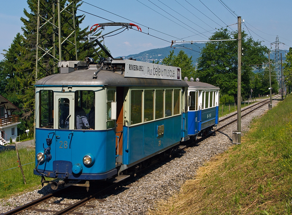 Triebwagen Ce 2/3 ex 28 der TL (Transports publics de la rgion lausannoise (deutsch ffentliche Transporte der Region Lausanne)), ex Genve Veyrier 23, BVB 18, dahinter mit dem Steuerwagen Nr. 57 ex BVB (Bex–Villars–Bretaye) kommen von Blonay hoch, hier am 27.05.2012 bei Chaulin. 

Der Triebwagen Ce 2/3 wurde ursprnglich 1913 als Zweiachser fr die Genve Veyrier als Nr. 23 von SWS und SAAS gebaut. Bereits 1919 ging er an die TL. Die Werksttte der TL baute ihn1948 um, die Aufbauten wurden modernisiert und der Wagen bekam eine zustzliche Mittelachse um die Antriebsachsen beim Durchfahren von Kurven zu fhren. Der Verschlei wurde somit stark reduziert und der Komfort stark verbessert. 1963 wurde die Jorat-Linie stillgelegt und der Triebwagen, sowie ein weiterer, gingen an die BVB. Der ex TL Ce 2/3 – 28 wurde 1976 an die Blonay-Chamby verkauft und ist eines der letzten berbleibsel der Lausanner Straenbahnen.

Der 8,83 m lange und 5 t schwere 2-achsige Beiwagen wurde 1930 von SIG fr die VMCV (Transports publics Vevey–Montreux–Chillon–Villeneuve) gebaut. Nach der kompletten Einstellung der Straenbahn 1958 (Umstellung auf den Trolleybus Vevey–Villeneuve) wurde der Beiwagen an die BVB verkauft. Lange Zeit war der Beiwagen als Leihgabe bei den TPC, Bahnstrecke Bex–Villars–Bretaye, bis er 2011 als BVB C2 57 zur Museumsbahn zurckgekehrte, seit 2013 ist er nun wieder in den ursprnglichen VMCV C2 57 umbezeichnet. Nun fhrt er nicht an der Waadtlnder Riviera, sondern etwas oberhalb.

TECHNISCHE DATEN des Ce 2/3 – 28
Spurweite: 1.000 mm
Achsformel: A 1 A
Lnge ber Puffer: 11.030 mm
Achsabstand: 2 x 2.100 mm (4.200 mm)
Dienstgewicht: 15.8  t
Treibraddurchmesser: 880 mm (Laufrad ist wesentlich kleiner)
Hchstgeschwindigkeit.:  55 km/h
Leistung: 2 x 88 kW = 176 kW
Getriebebersetzung: 1:5,93
Spannung: 900 V DC

