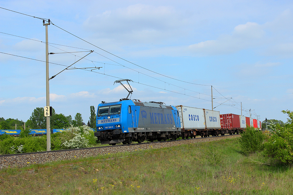 05.05.2014 16:15 Uhr - Metrans 185 510 fährt mit einem Containerzug in Richtung Salzwedel, während im Hintergrund auf der Wittenberger Schiene der LKW-Walter Rostock - Novara auf Einfahrt in den Güterbahnhof wartet.