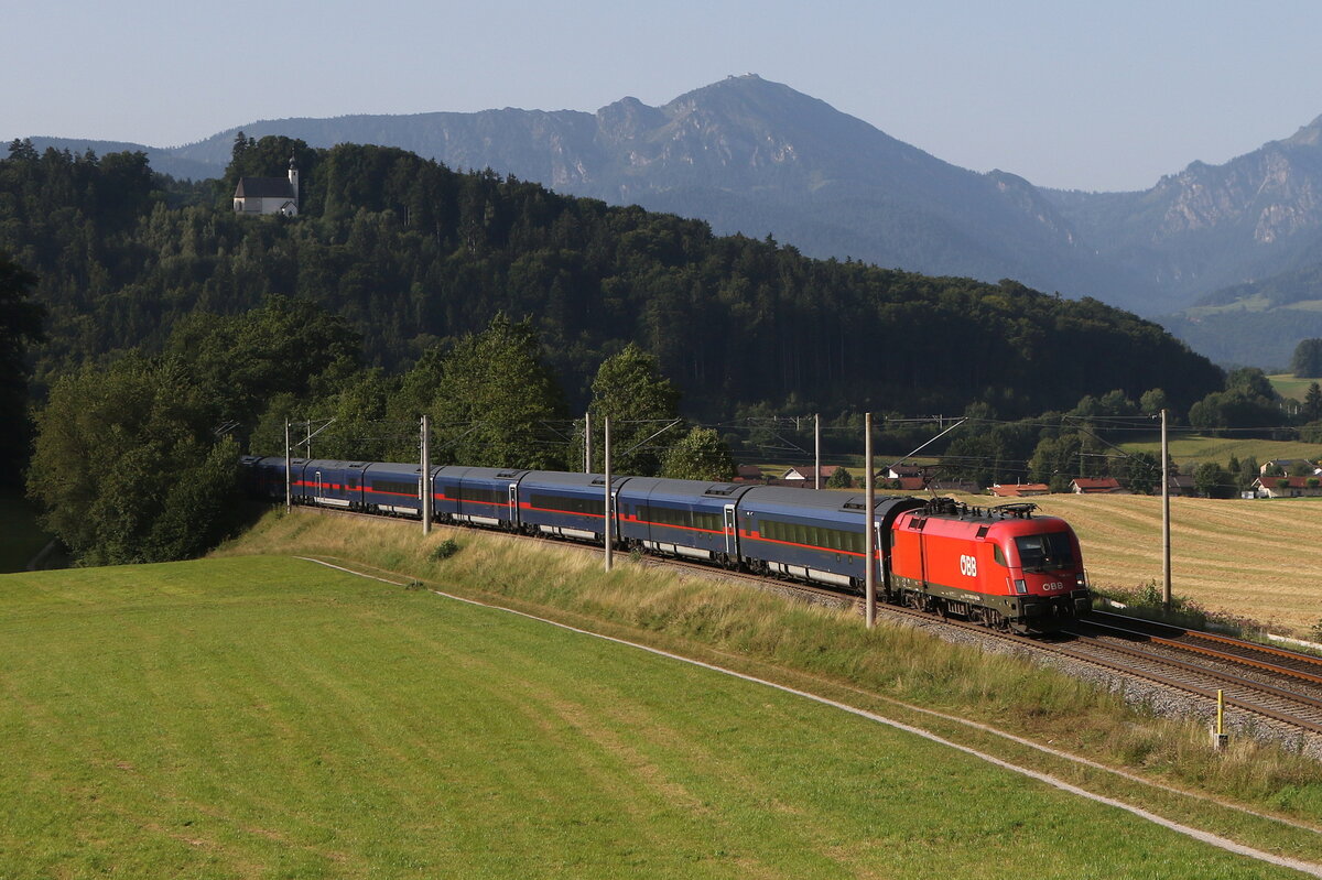 1016 017 war mit einem  Nightjet  am 13. August 2025 bei Vachendorf im Chiemgau in Richtung Salzburg unterwegs.