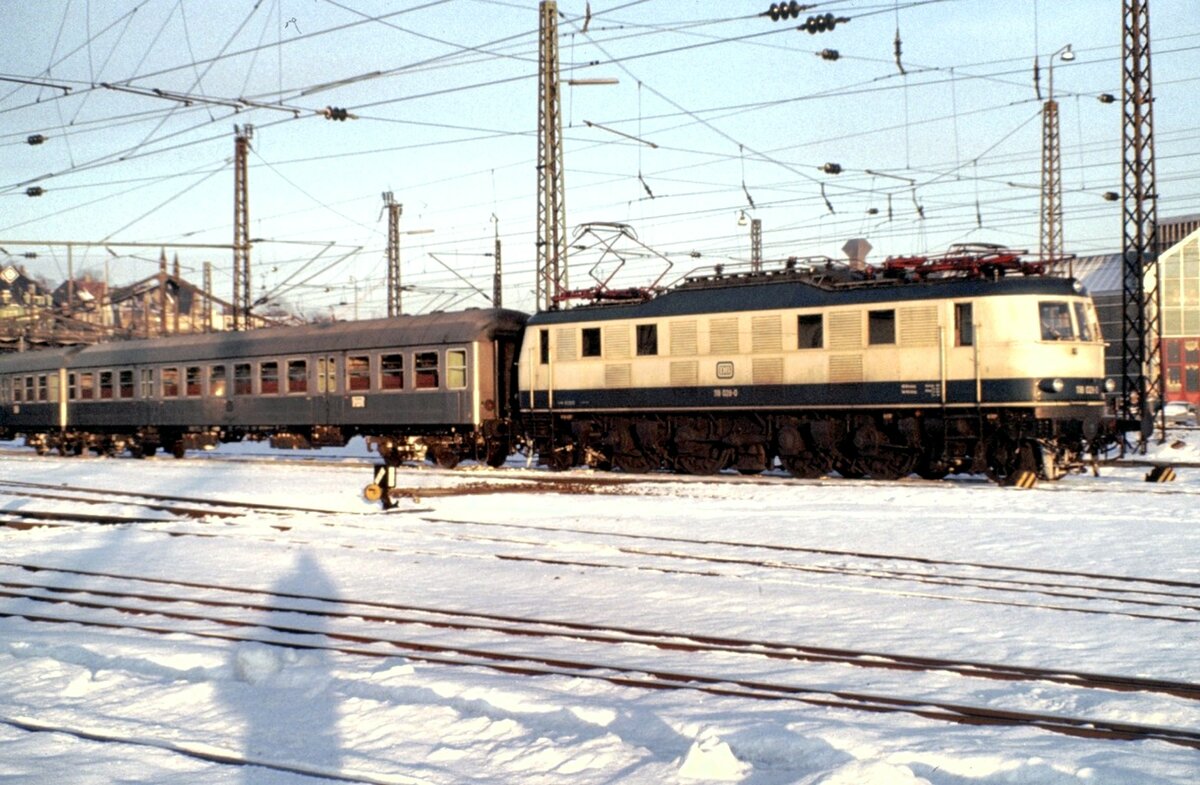 118 028-0 mit Nahverkehrszug in Ulm wartet auf den Einsatz nach Regensburgam 07.12.1980.