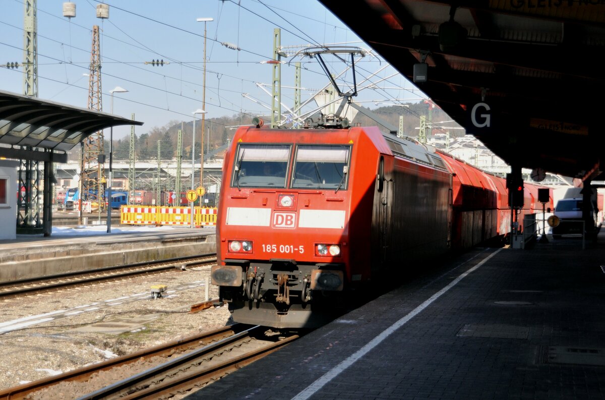 185 001-5 mit Kalkzug auf Gleis 1 wartet am Bahnsteig auf die Überholung eines JCE 3, am 09.02.2023.