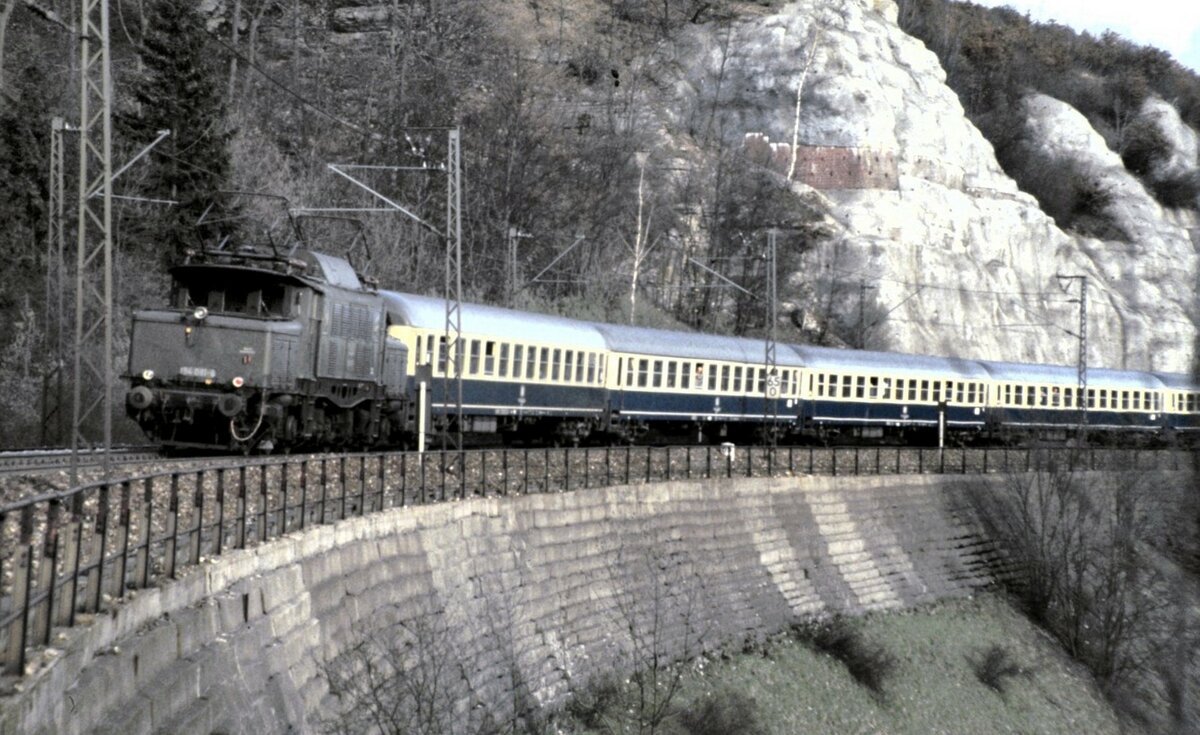 194 081-6 gibt Schubhilfe für einensehr langen Intercity auf der Geislinger Steige, hier auf dem Mühltalfelsendamm am 27.03.1982.