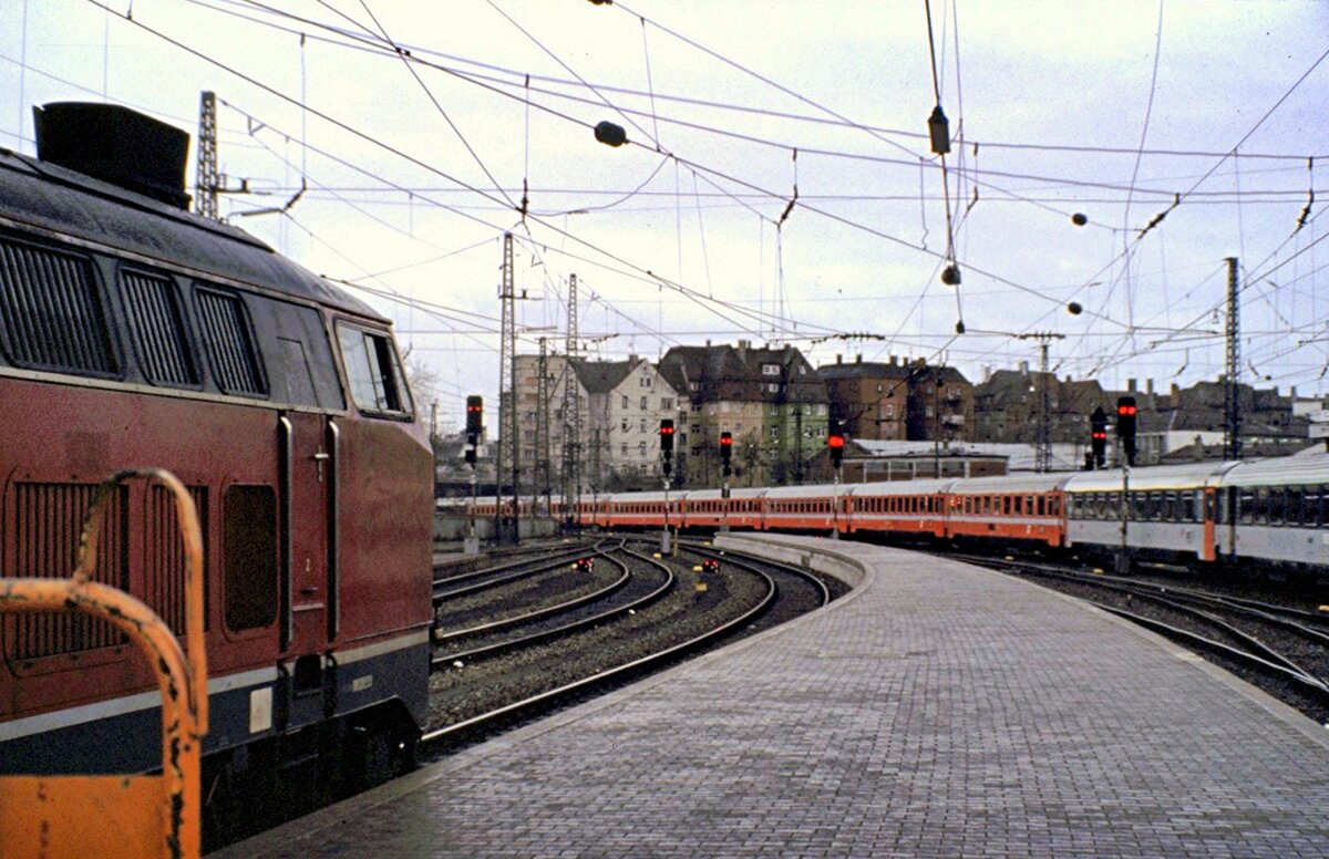 210 005-5 in Ulm auf den  Bayerischen Gleisen  Gleis 25, wartet auf Abfahrerlaubnis nach Oberstdorf, während auf Gleis 2 der Eurocity  Mozart  in Richtung Wien ausfährt, Ulm im Mai 1980.