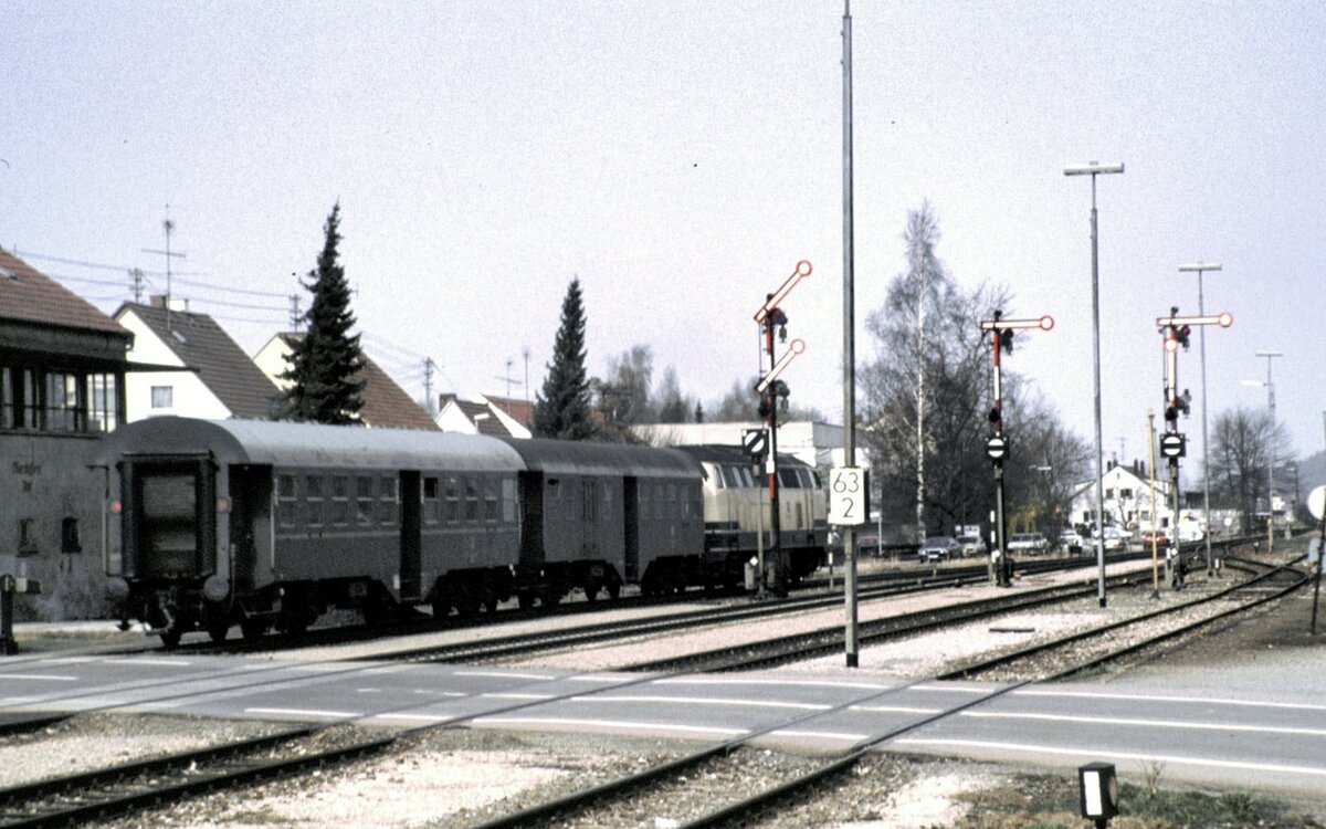 215 094-4 mit Umbauwagen mit Gepäckabteil und Schwanenhals-Drehgestellen und einem Umbauwagen der Allgäu-Zollern-Bahn in Illertissen (grüner Streifen) im Februar 1990.