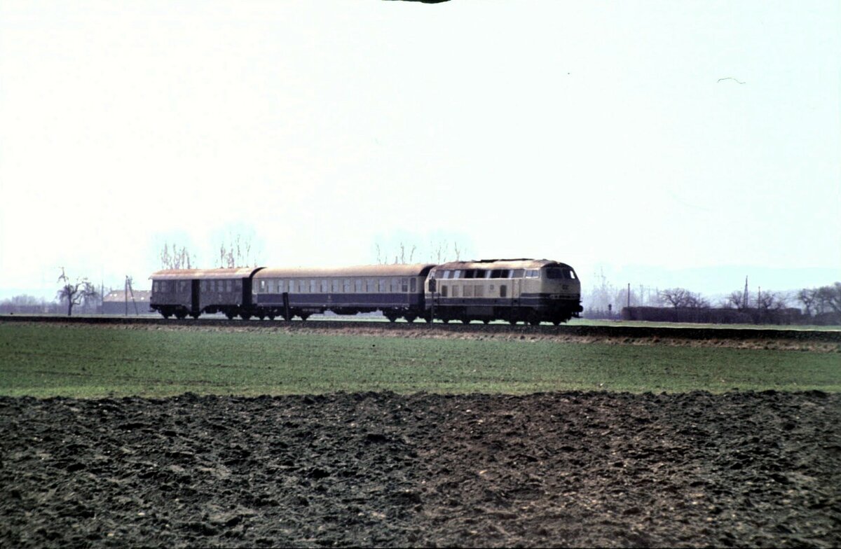 215 mit Nahverkehrszug aus Reisezugwagen Bm und Umbauwagen mit Gepäckabteil BDyg bei Illertissen im Februar 1990.