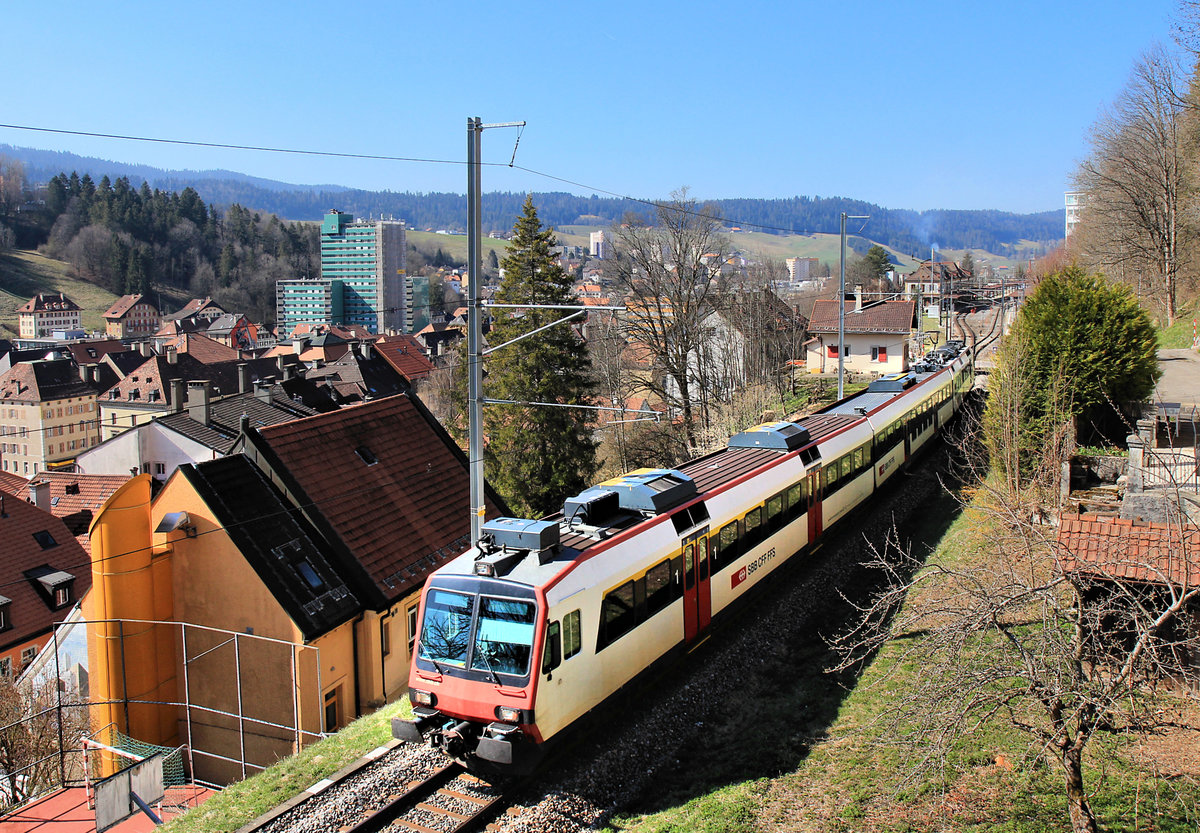 Abstieg zum Bahnhof Le Locle, NPZ Domino-Zug mit Steuerwagen ABt 50 85 39-43 837 zuhinterst. Der Bahnhof Le Locle befindet sich in einiger Höhe am Hang oben; früher fuhren ein paar SBB-Züge von da noch hinunter zum Talboden nach Le Locle Col-des-Roches. Diese Strecke wird nur noch von den ganz wenigen SNCF-Triebwagen nach Besançon planmässig befahren, und auch das nicht mehr seit dem 1.März (bis Ende Oktober). 23.April 2021