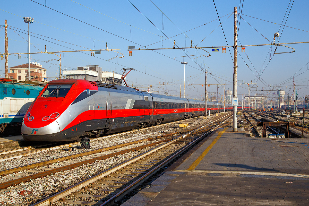 Ausfahrt eines sehr langen  Frecciarossa  (deutsch: roter Pfeil) der Trenitalia (100-prozentige Tochtergesellschaft der Ferrovie dello Stato) am 29.12.2015 vom Bahnhof Milano Centrale (Mailand Zentral). Der Frecciarossa ist eine Zuggattung für Züge mit einer Höchstgeschwindigkeit von 300 km/h. Hier ist es der ETR 500 - 56 ein ETR 500 der 2.Serie. ETR steht ElettroTreno Rapido.

Diese Züge bestehen aus zwei Triebköpfen vom Typ E.404B und aus zwölf Mittelwagen, ETR 500.31 bis 60 komplett der 2.Serie. Bei den ETR 500.01 bis 30 sind nur die beiden Triebköpfe aus der 2.Serie, die Mittelwagen dagegen stammen aus der 1.Serie der ETR 500 (Mono). 

Durch die begrenzte Stromstärke des Gleichstromnetzes können die Hochgeschwindigkeitszüge nur für Geschwindigkeiten bis zu 250 km/h ausreichend mit Energie versorgt werden. Deshalb entschied sich die italienische Staatsbahn in den 1990er Jahren, weitere Neubau-Schnellfahrstrecken mit Wechselstrom (25 kV, 50 Hz) zu betreiben.

Da die erste Serie der ETR 500 nur für das Gleichstromnetz geeignet ist, wurde ab 1996 eine zweite Serie ETR 500 bestellt und geliefert, die sowohl im Gleichstrom- als auch im Wechselstromnetz fahren kann. Die Zweisystem-Fahrzeuge werden Politensione (deutsch: Mehr-Spannung) genannt. Es gab auch mal zwischenzeitlich Dreisystem-Fahrzeuge (ETR 500 F), die auch unter 1.5 kV DC fahren konnten, diese wurden aber wieder zurückgebaut. Diese waren für den Verkehr nach Frankreich gedacht, bekamen aber dort keine Zulassung.

Die zulässige Höchstgeschwindigkeit der ETR 500 der zweiten Serie von 300 km/h wird im regulären Betrieb aber nur mit Wechselstrom auf neueren Schnellfahrstrecken Italiens erreicht.

Im Gegensatz zur ersten Serie werden bei der zweiten Serie Einholmstromabnehmer verwendet. Die Triebköpfe verfügen jeweils über einen Abnehmer für Gleichstrom und einen Abnehmer für Wechselstrom. Äußerlich unterscheiden sich die beiden Bauserien durch starke Unterschiede des „Gesichts“. Die Front der zweiten Serie wurde aufgelockert und rundlicher gestaltet, besonders betont durch die getrennt angeordneten Spitzensignale, während die Frontscheiben kleiner und rechteckig ausgeführt wurden. Wobei ja die Triebköpfe (E.404A) der ersten Serie zu Lokomotiven der Baureihe E.414 umgebaut wurden.


TECHNISCHE DATEN:
Von einem Triebkopf E.404B
Spurweite:  1.435 mm (Normalspur)
Achsformel: Bo'Bo'
Länge: 20.250 mm
Höhe: 4.000 mm
Breite: 3.020 mm
Drehzapfenabstand:  11.450 mm
Achsabstand im Drehgestell: 3.000 mm
Dienstgewicht: 68 t
Höchstgeschwindigkeit: 300 km/h
Dauerleistung: 4.400 kW (4 x 1.100 kW) pro Triebkopf
Treibraddurchmesser:  1.100 mm
Stromsysteme: 3000 V DC und 25 kV 50 Hz AC

Daten der Mittelwagen:
Länge: 26.100 mm
Drehzapfenabstand:  19.000 mm
Achsabstand im Drehgestell: 3.000 mm
Eigengewicht: 40 t

Gesamtzug Daten:
Achsformel: Bo'Bo' (12x 2'2') Bo'Bo'
Gesamtzuglänge: 353.700 mm (bei 12 Mittelwagen)
Gesamteigengewicht: 616 t
Dauerleistung: 8.800 kW
Anfahrzugkraft:  400 kN